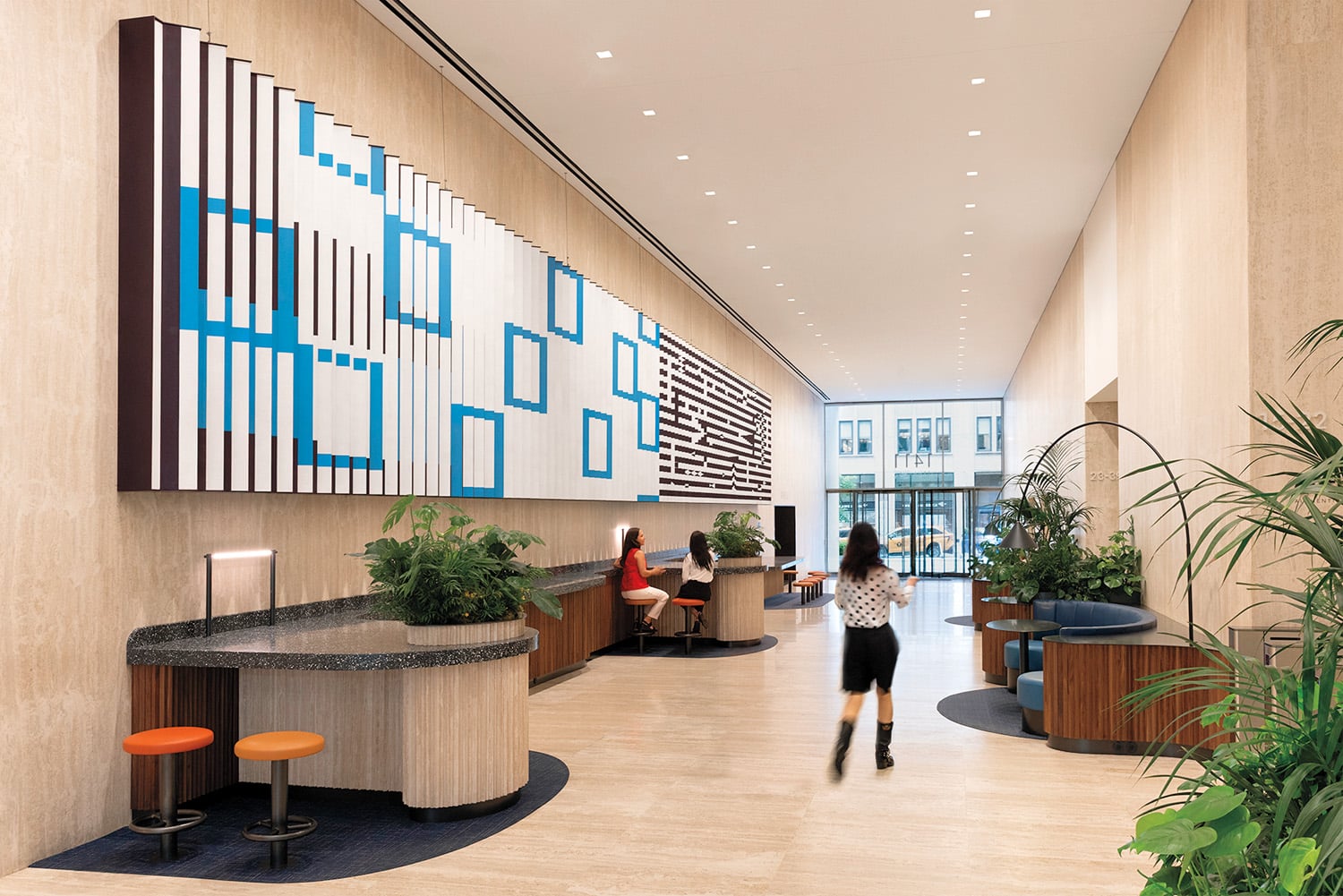 people in hallway with blue square wall art