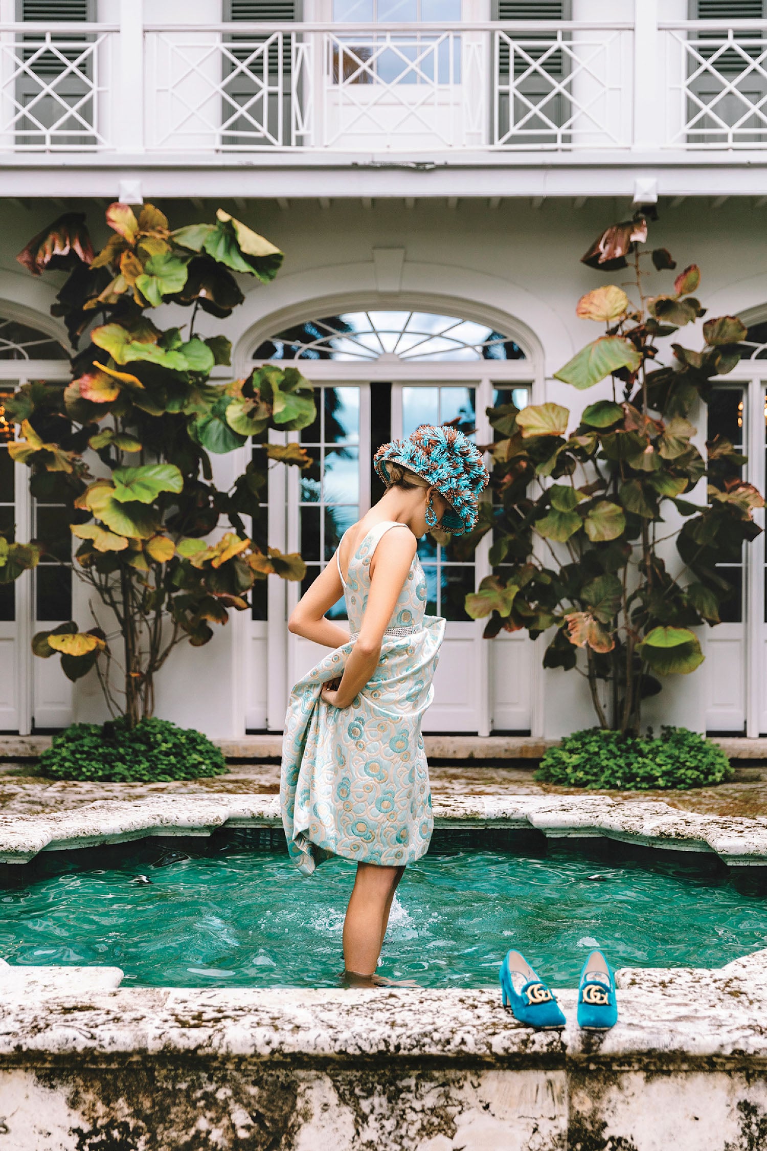 A woman in a blue dress standing in a fountain.