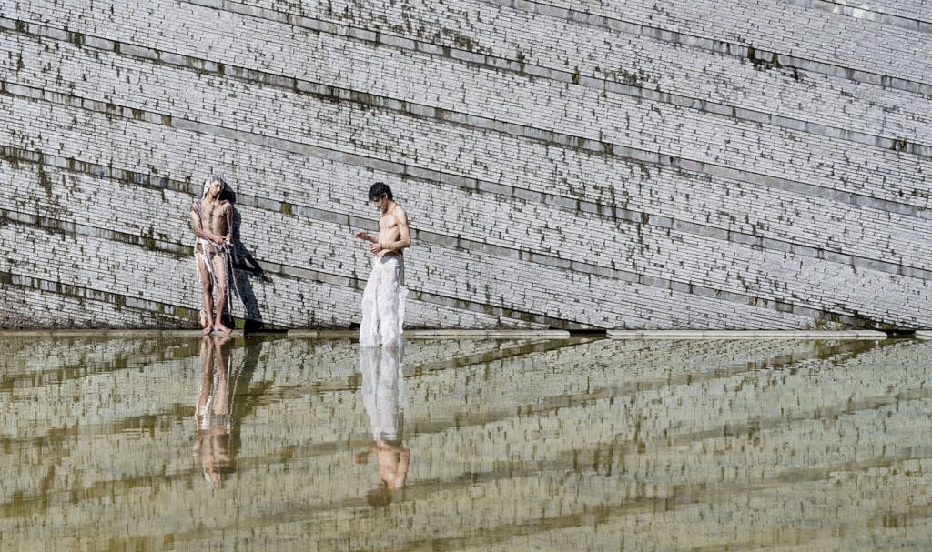 A couple standing in a pool with a froth of water.