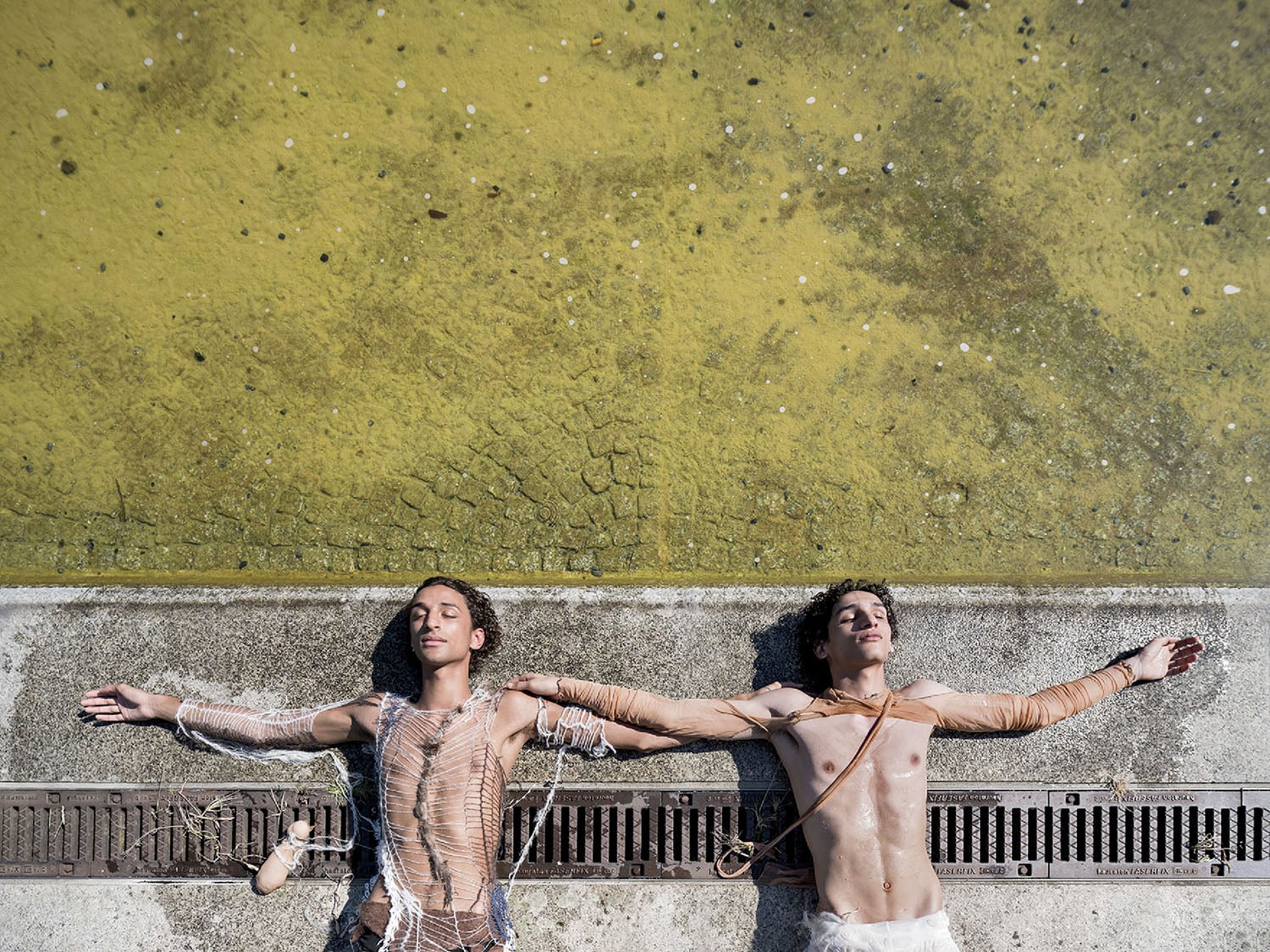 Two people standing on a sidewalk with their arms outstretched.