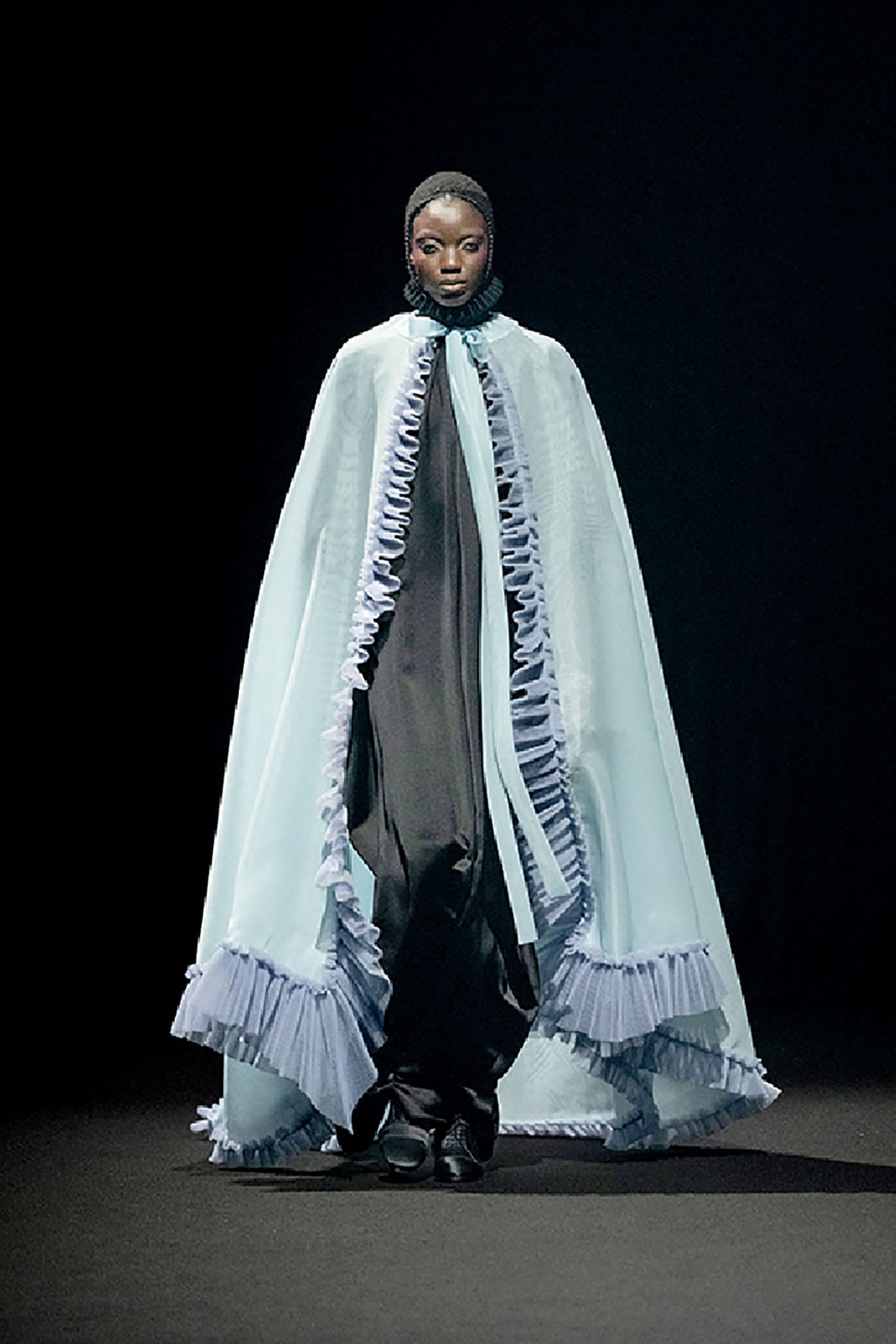 A woman in a white dress and a black cape.