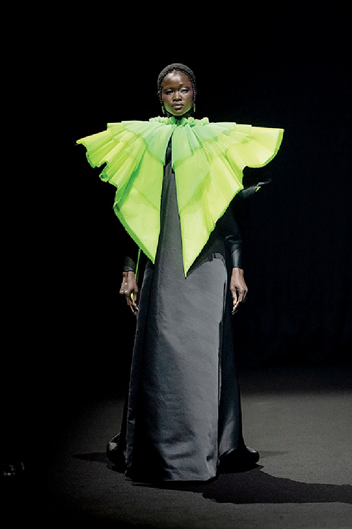 A woman in a black dress and green cape.