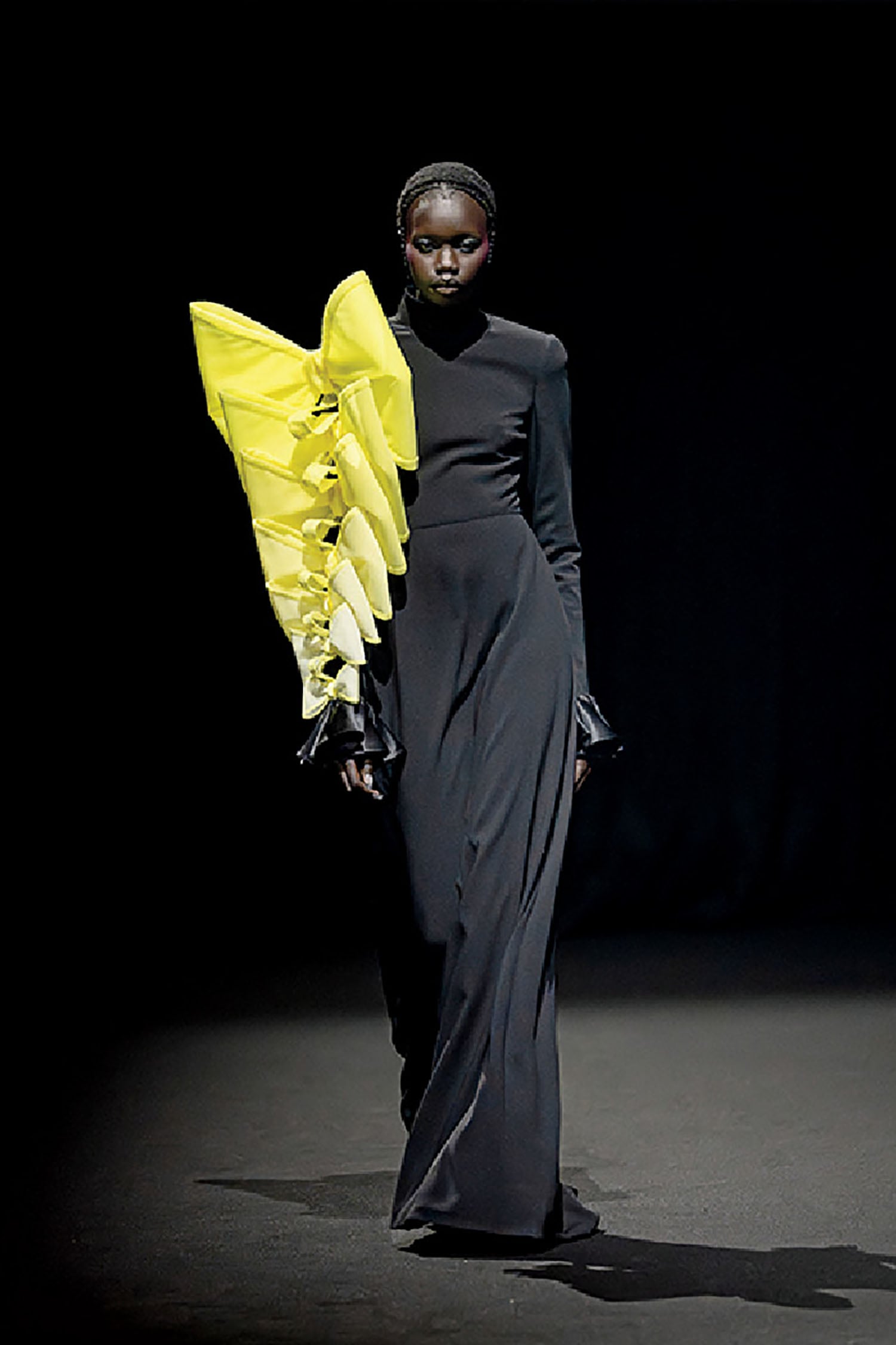 A woman in a black dress and yellow scarf.