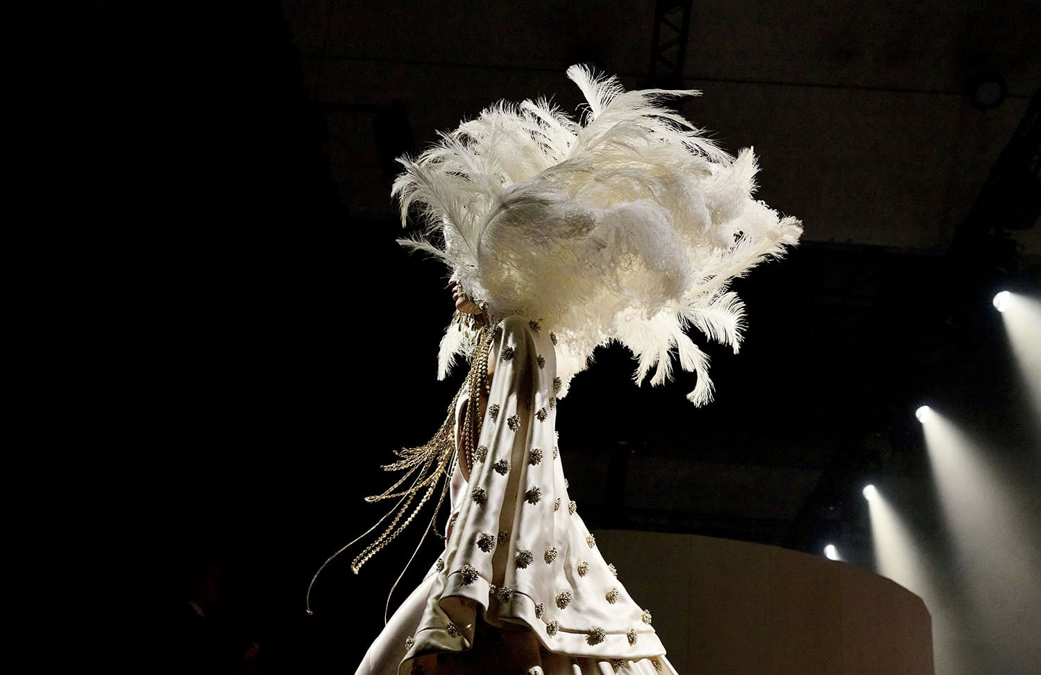 A woman in a white dress and feather hat.