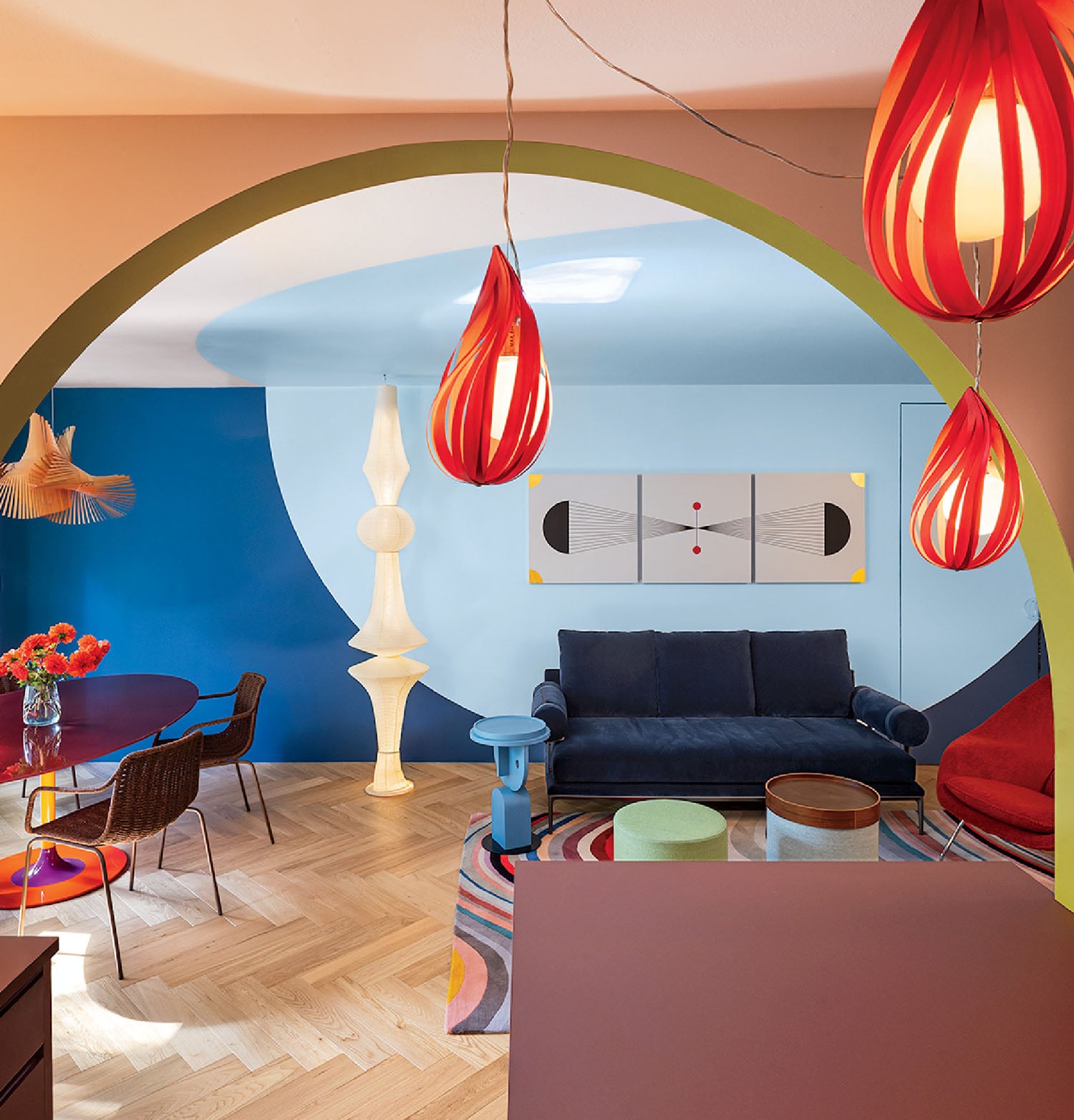A living room with a blue couch and a colorful wall.