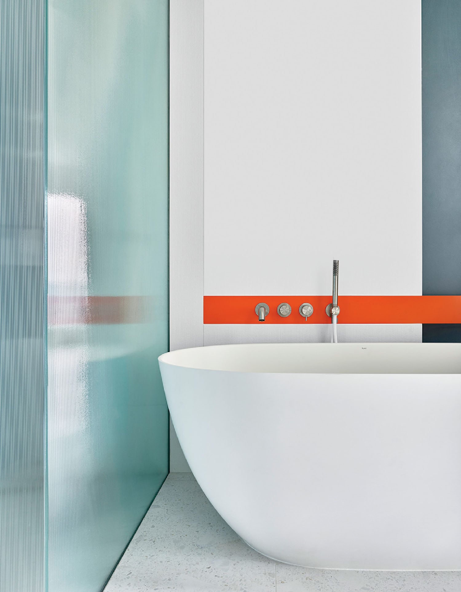 A bathtub in a bathroom with a blue and orange wall.