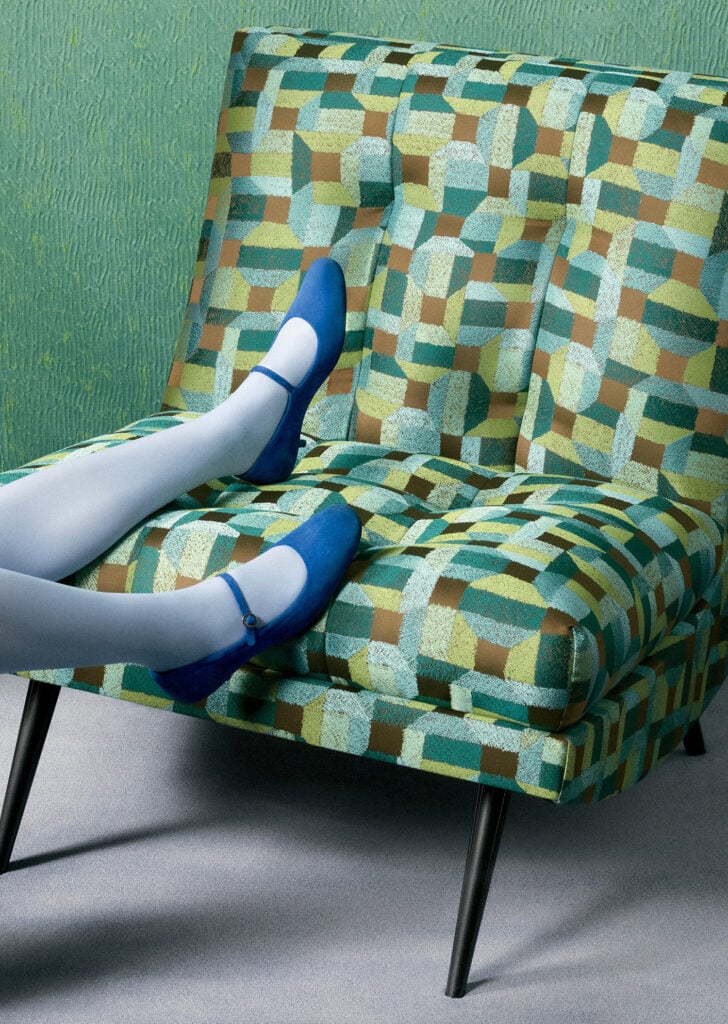A woman sitting on a chair with a blue shoe