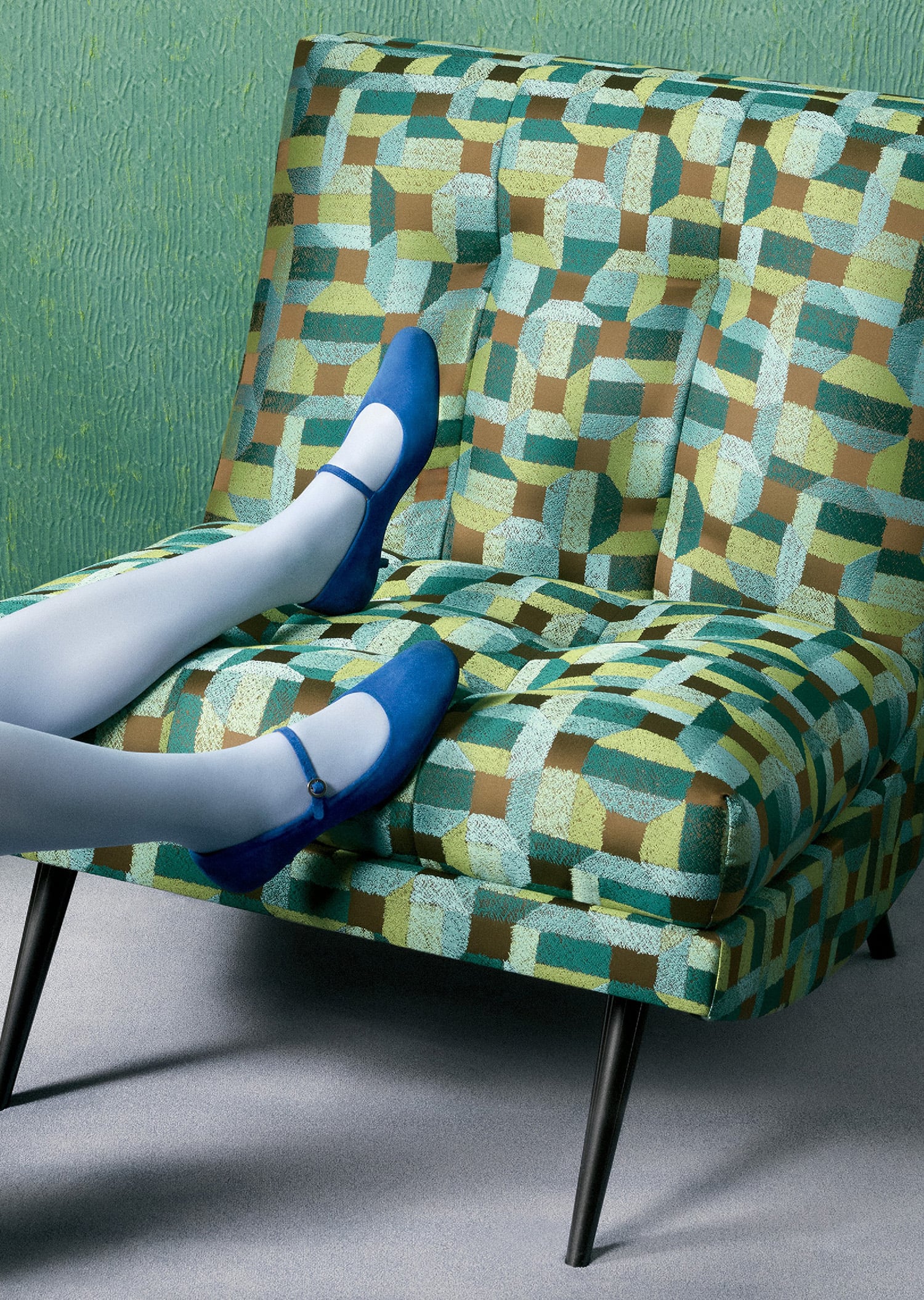 A woman sitting on a chair with a blue shoe