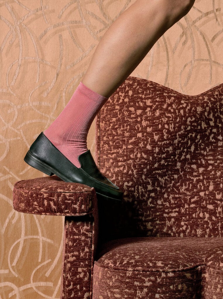 A woman ' s legs and feet are shown in a chair