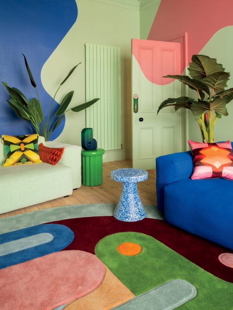 A living room with a colorful rug and a blue couch
