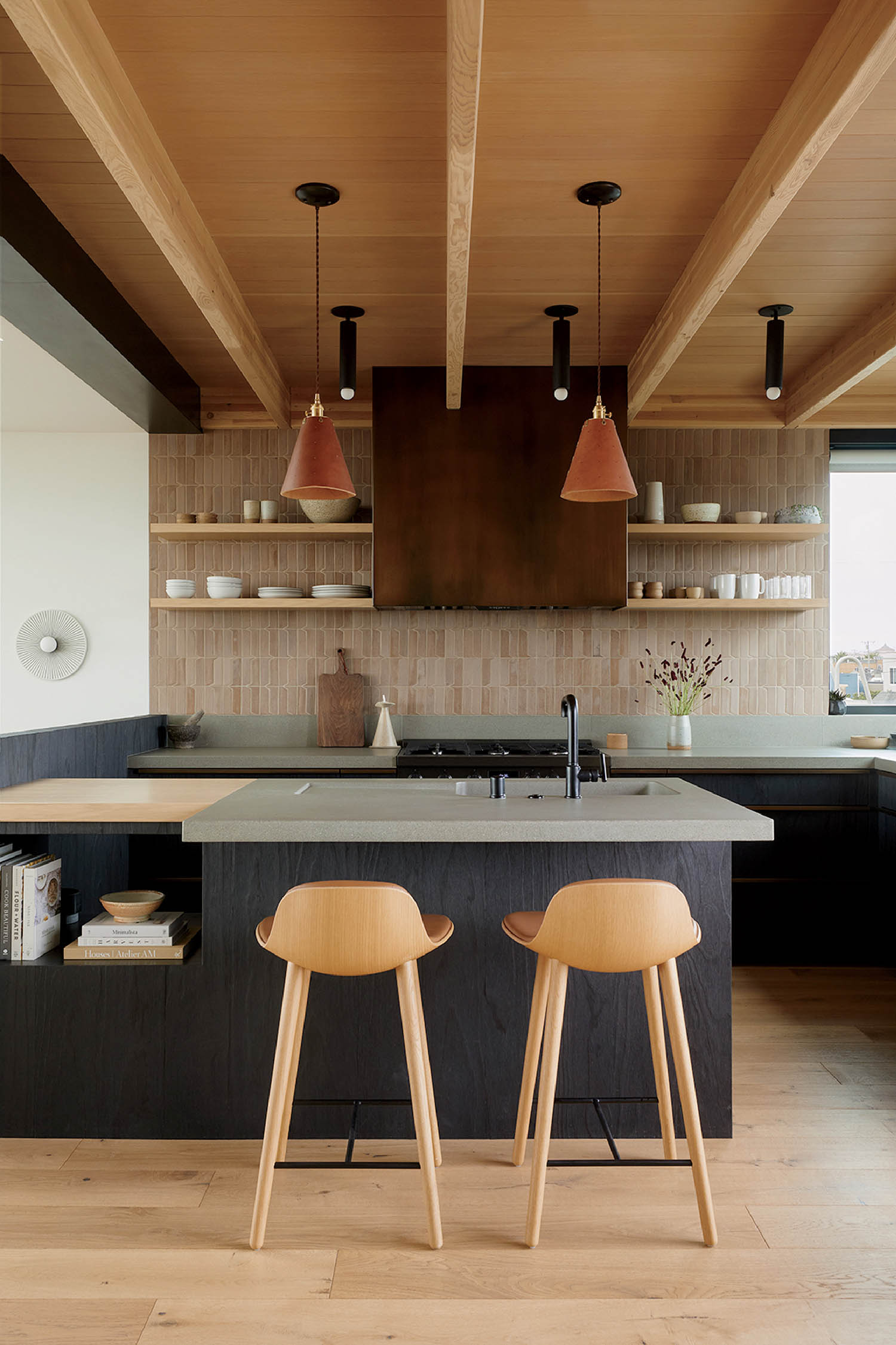 A kitchen with two stools and a large island.