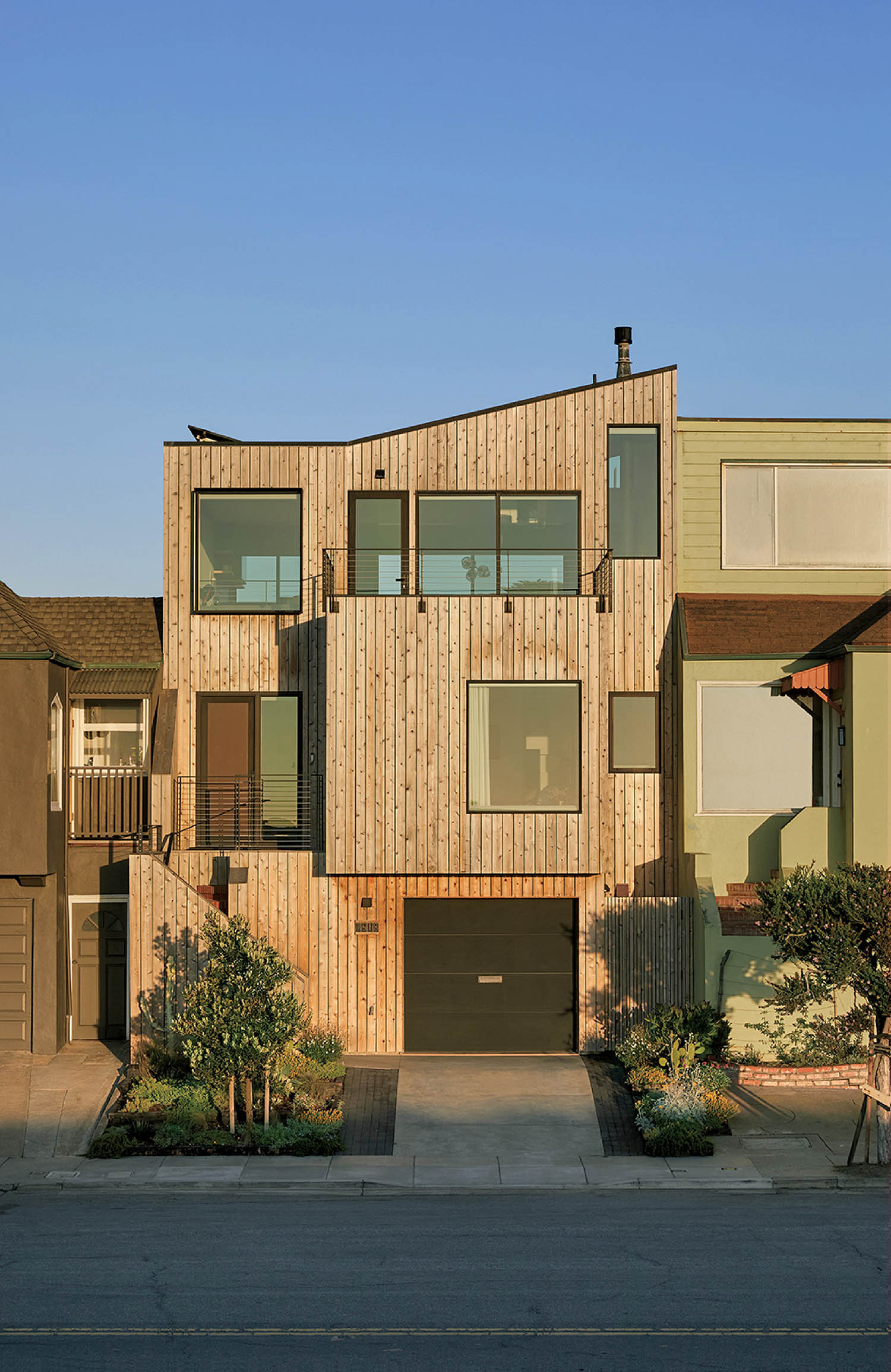 A house with a lot of windows and a lot of plants.