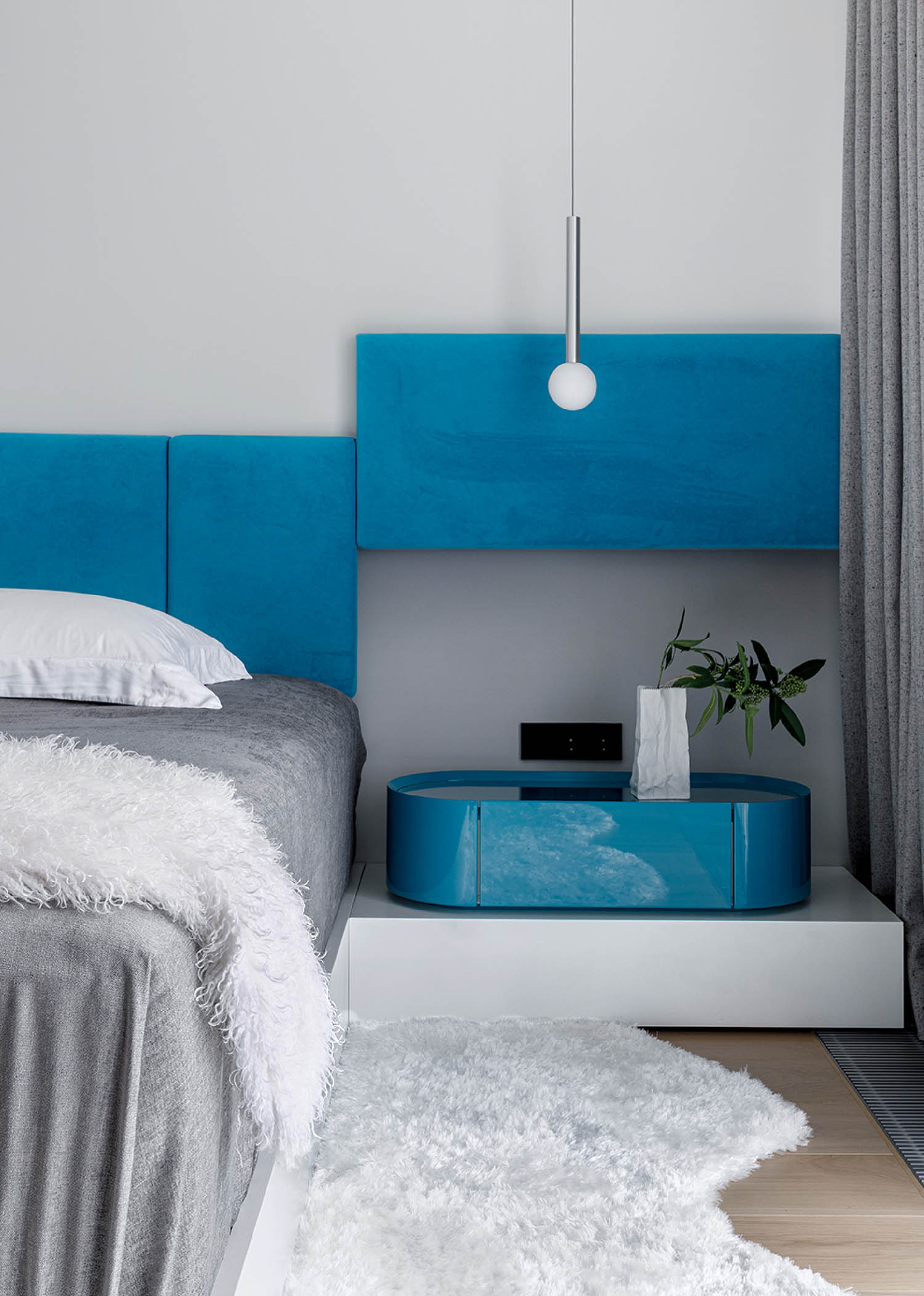 A bed with a blue headboard and a white rug.
