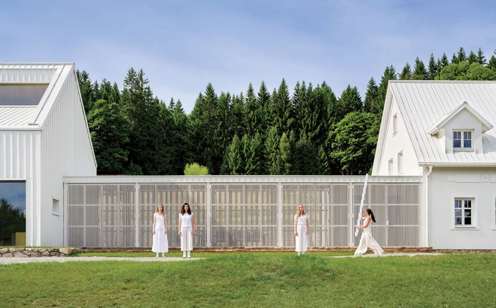 Two women walking in front of a white house.