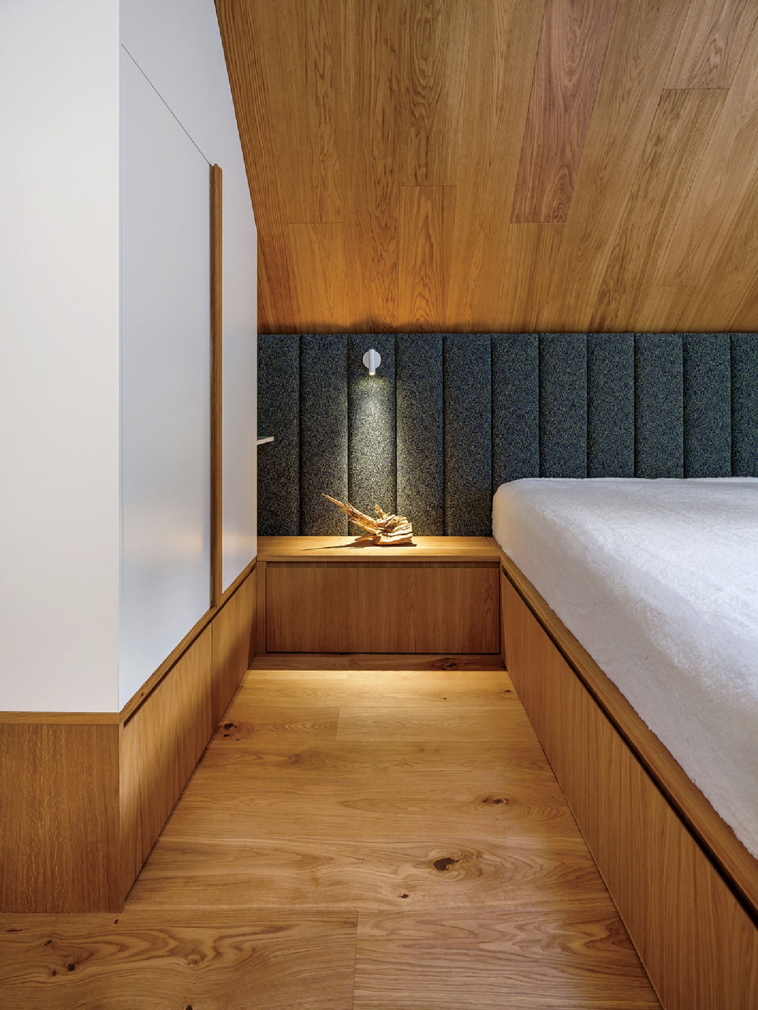 A bed in a room with a wooden wall.