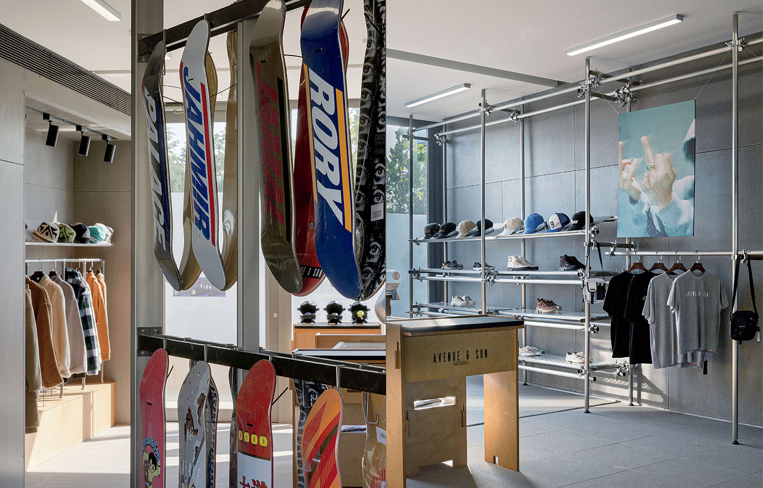 A modern retail store interior with skateboards on display, clothing racks, shelves with caps, and a large photograph on the wall.