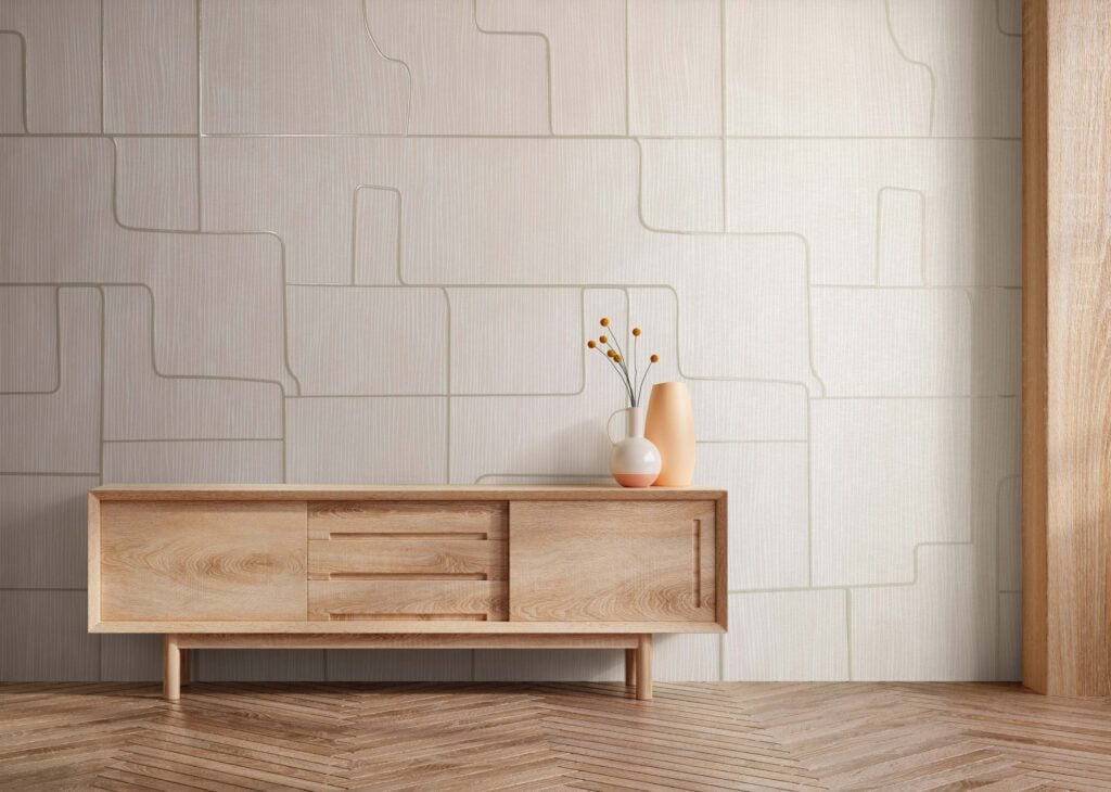 Minimalist room with a wooden sideboard, two vases with dried flowers on top, geometric light wood wall panels, and herringbone wood floor.