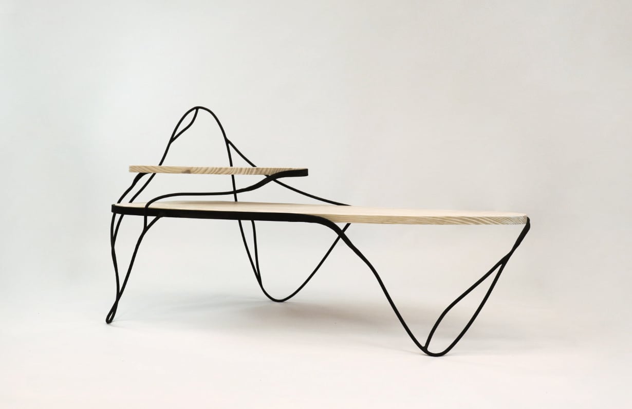 A bench with a light wooden seat and shelf, supported by thin, wavy black metal legs and frame, set against a plain white background.
