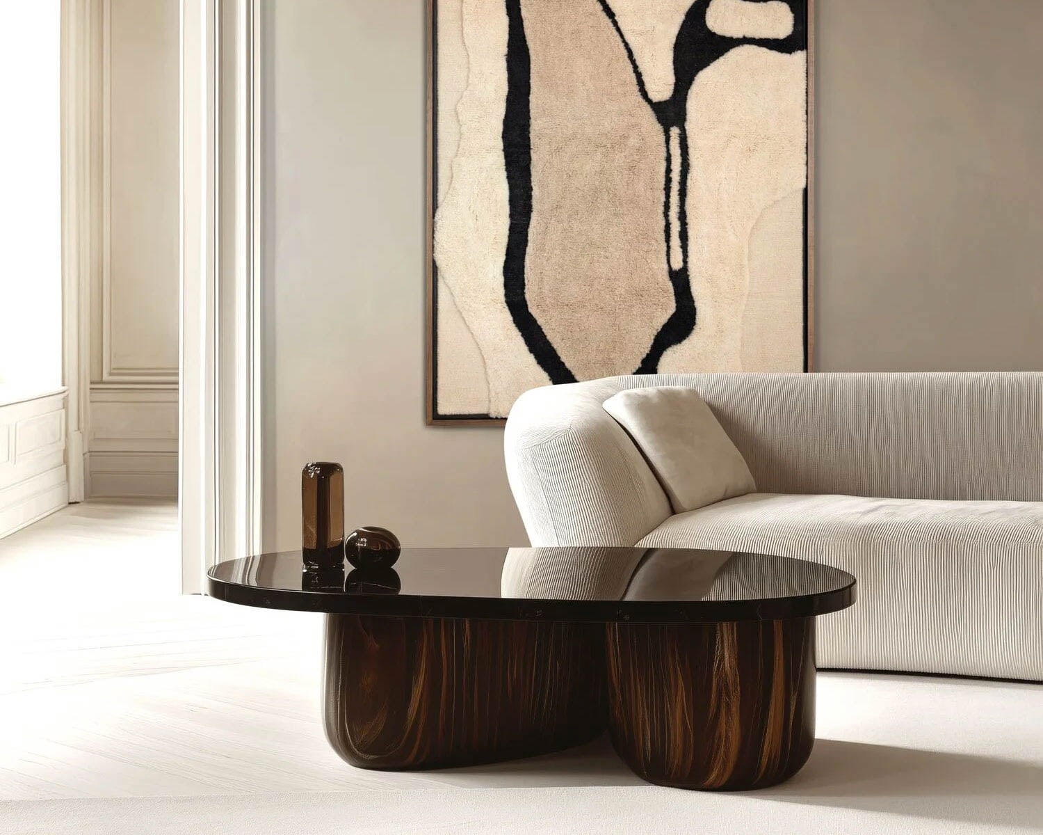 A modern living room with a white curved sofa, a dark wood coffee table, abstract wall art, and neutral-toned walls and flooring.