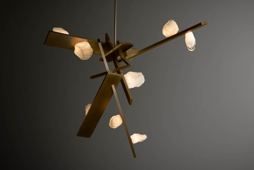 A modern chandelier with intersecting bronze rods and several frosted glass bulb covers arranged asymmetrically.