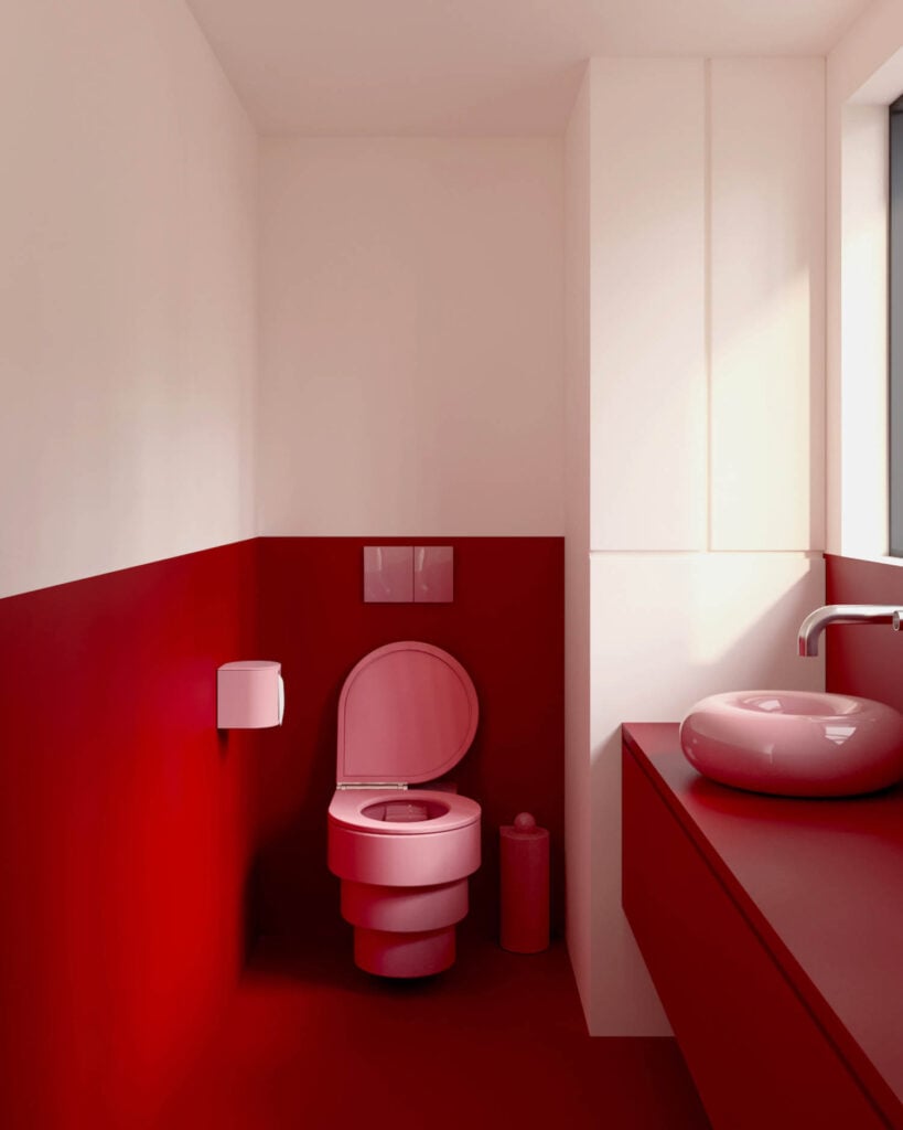 A modern bathroom with red and white walls, a pink toilet, matching pink sink, and countertop, featuring minimalist fixtures and a window letting in natural light.