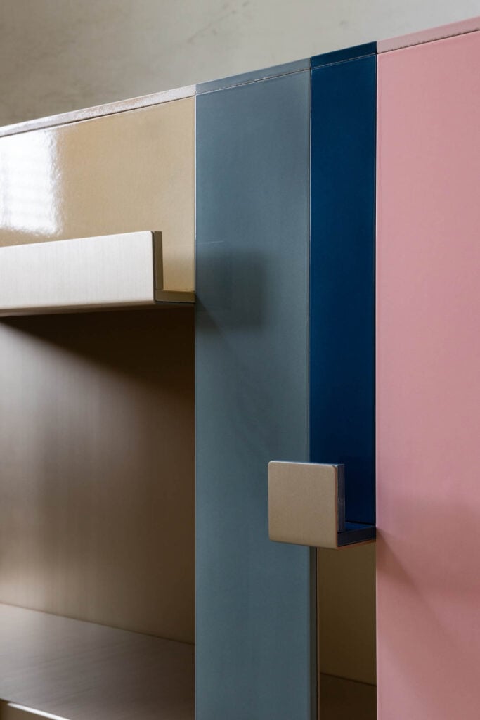 Close-up of a modern cabinet featuring beige, blue, and pink panels with geometric handles and a minimalist design.