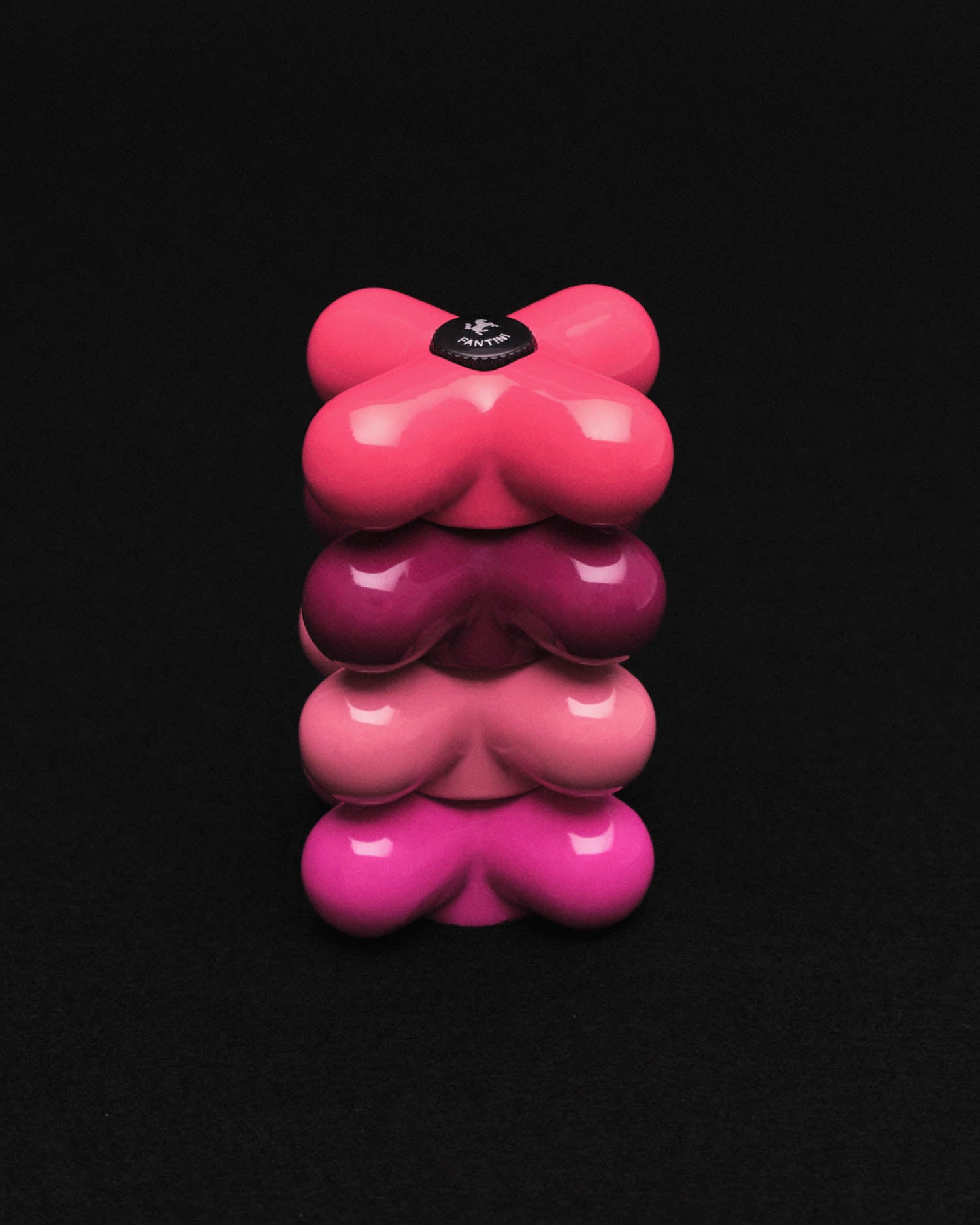 Four stacked, heart-shaped containers in varying shades of pink against a plain black background.