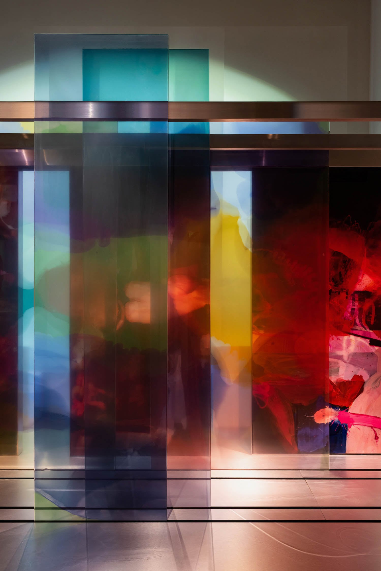 Translucent colored panels stand upright in a row, overlapping to create a layered effect with vibrant red, blue, yellow, and green hues illuminated by soft light.