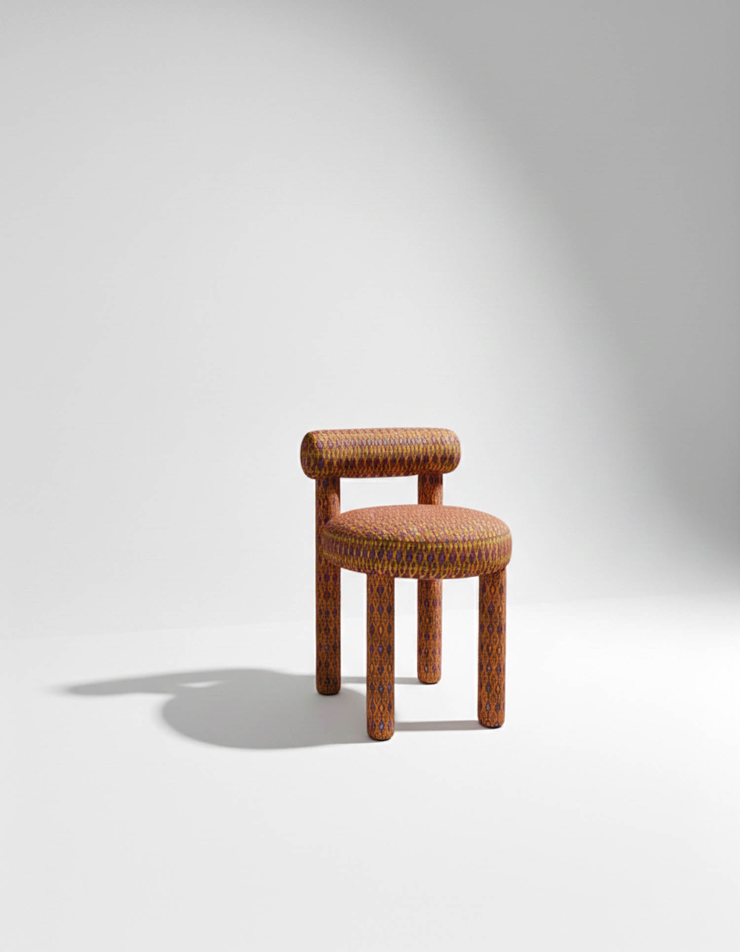 A patterned chair with cylindrical legs, a round seat, and a short rounded backrest, placed on a white surface with a plain background and soft shadow.