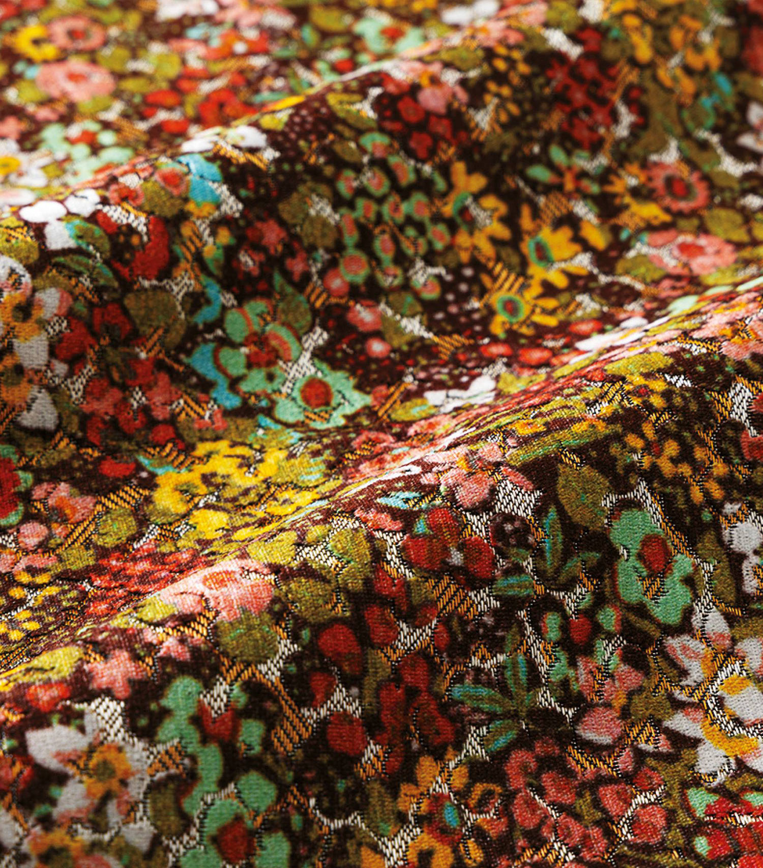 Close-up of colorful, densely patterned floral fabric with small flowers in red, green, yellow, and brown tones, showing the texture and folds of the material.