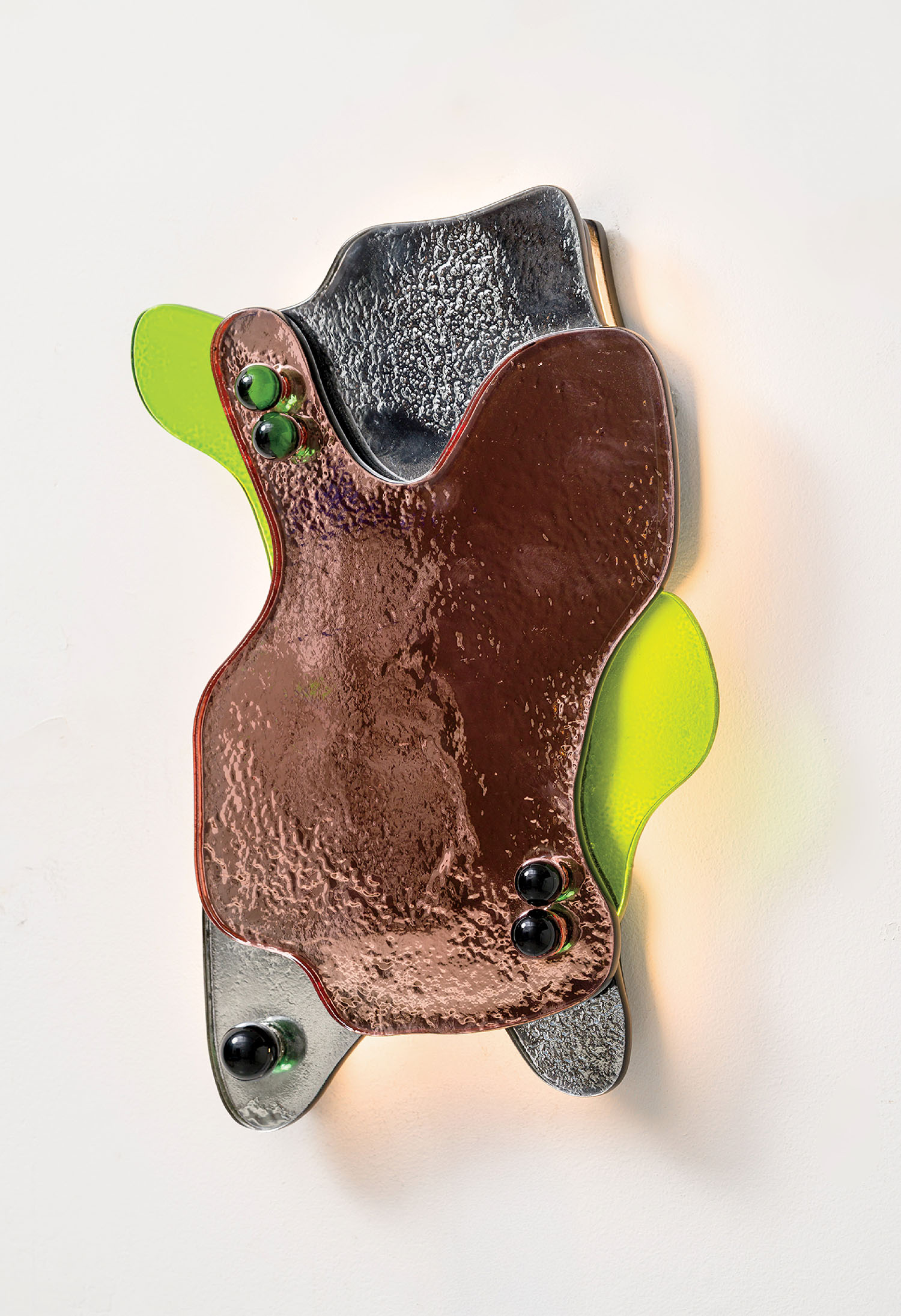 Abstract wall sculpture with textured glass shapes in brown, gray, and neon green, featuring several round glass accents, mounted on a white background.