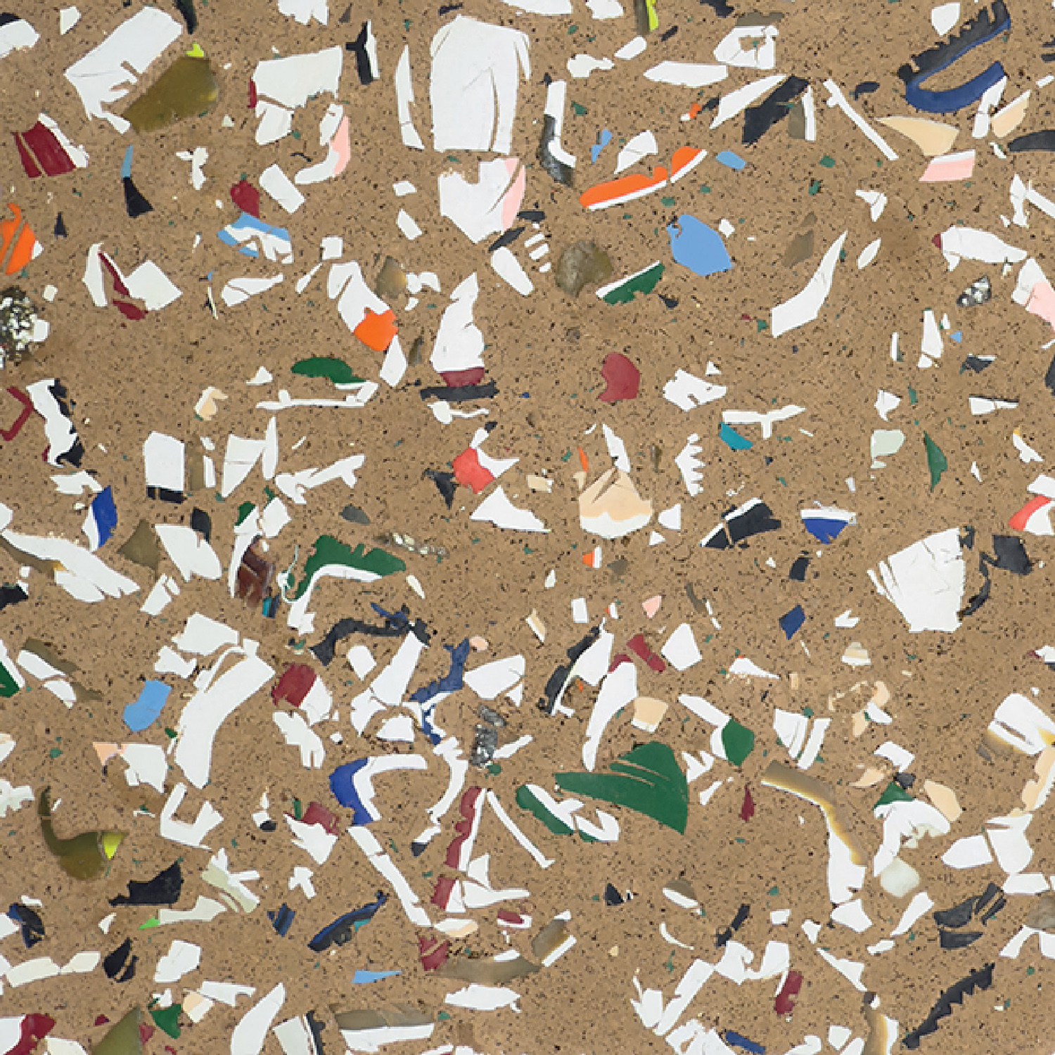 Close-up of a brown cork surface with scattered, irregularly shaped fragments of various colors, including white, green, blue, orange, and yellow.