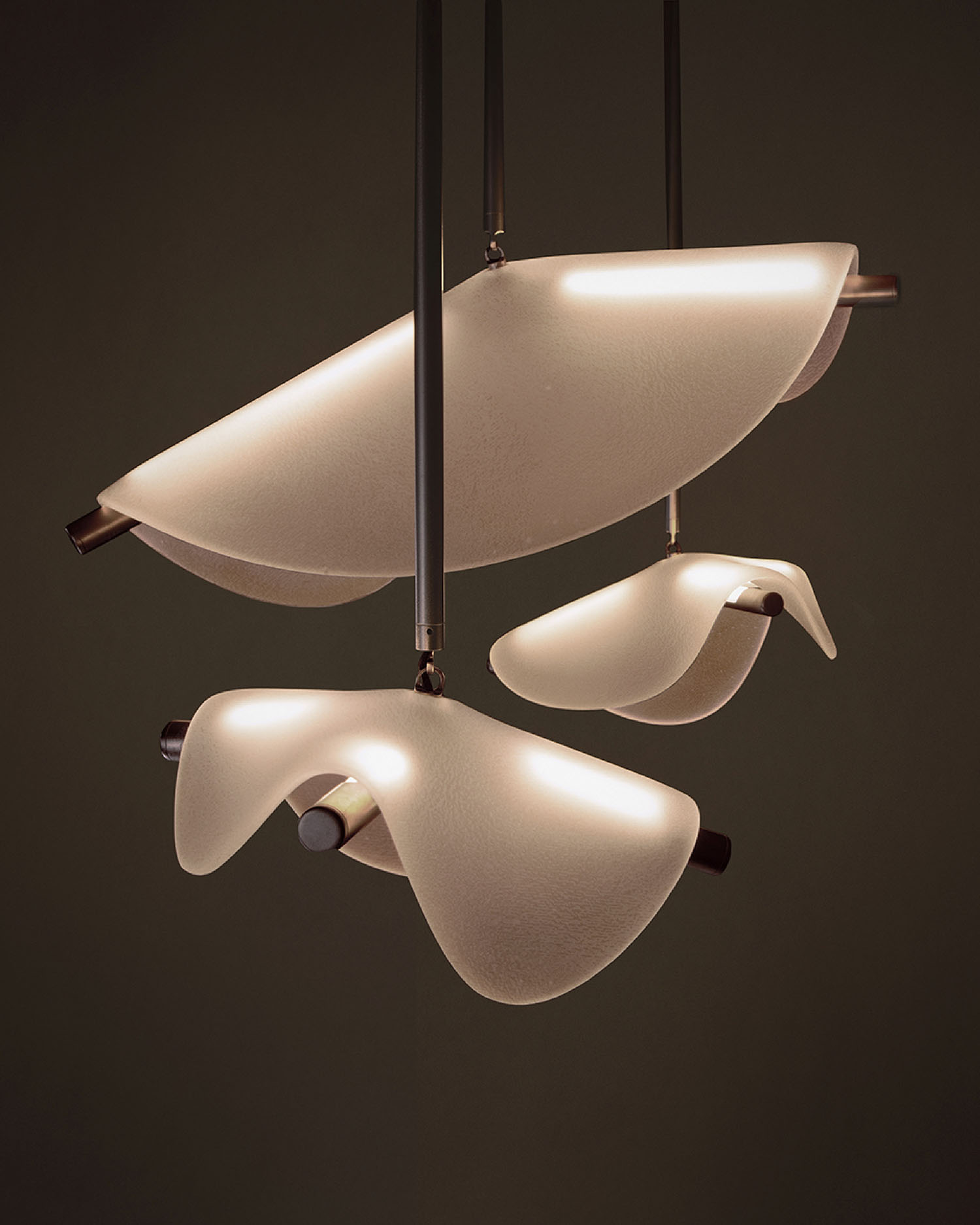 Three sculptural pendant lights with flowing, translucent white shades and dark metal rods, suspended against a plain, dark background.