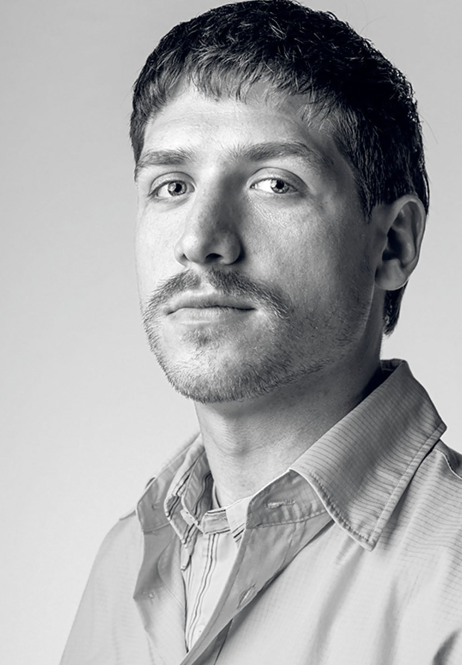 A man in a shirt looking up at the camera.