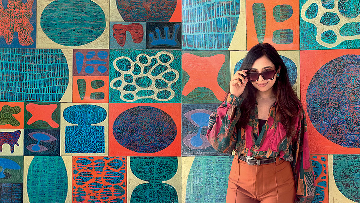 A woman standing in front of a colorful wall.