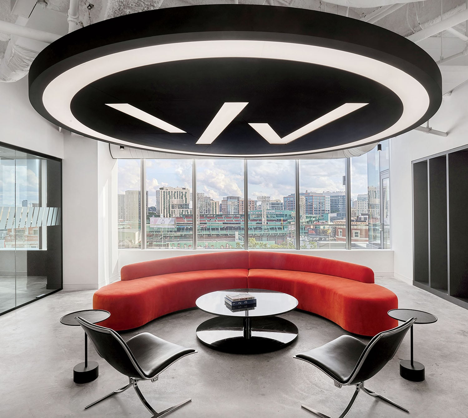 A red couch in a modern office with a view of the city.