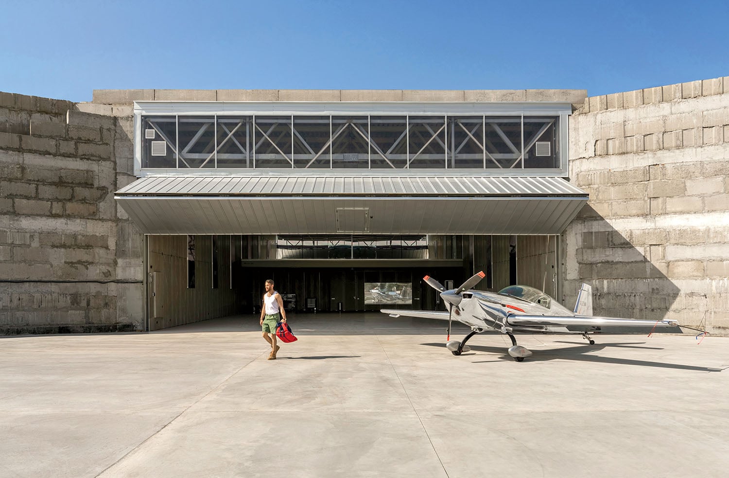 A man walking towards a small plane in a parking.