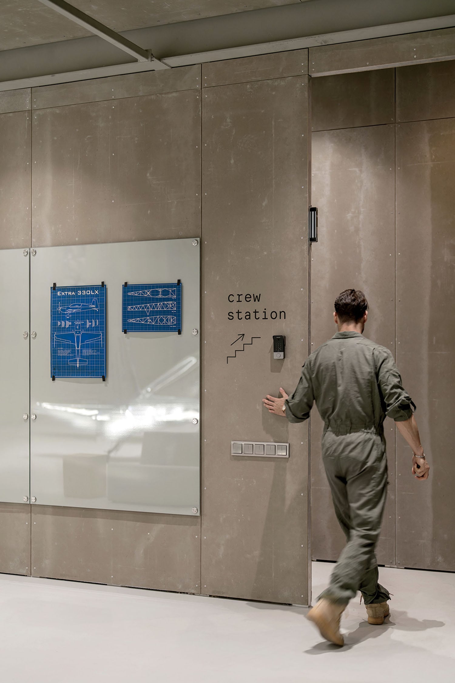 A man walking past a white wall with a sign on it.