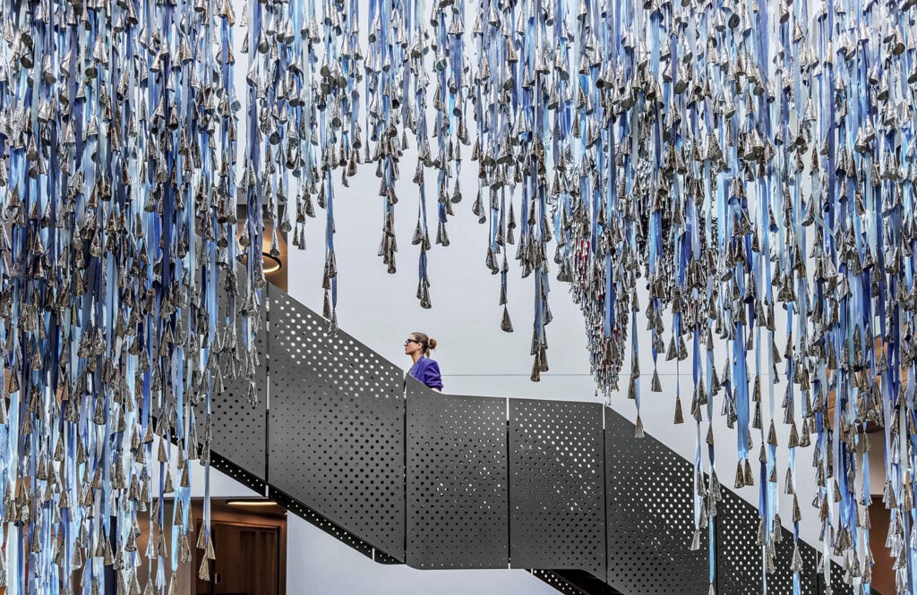 A woman is standing on a staircase made of blue ribbons.