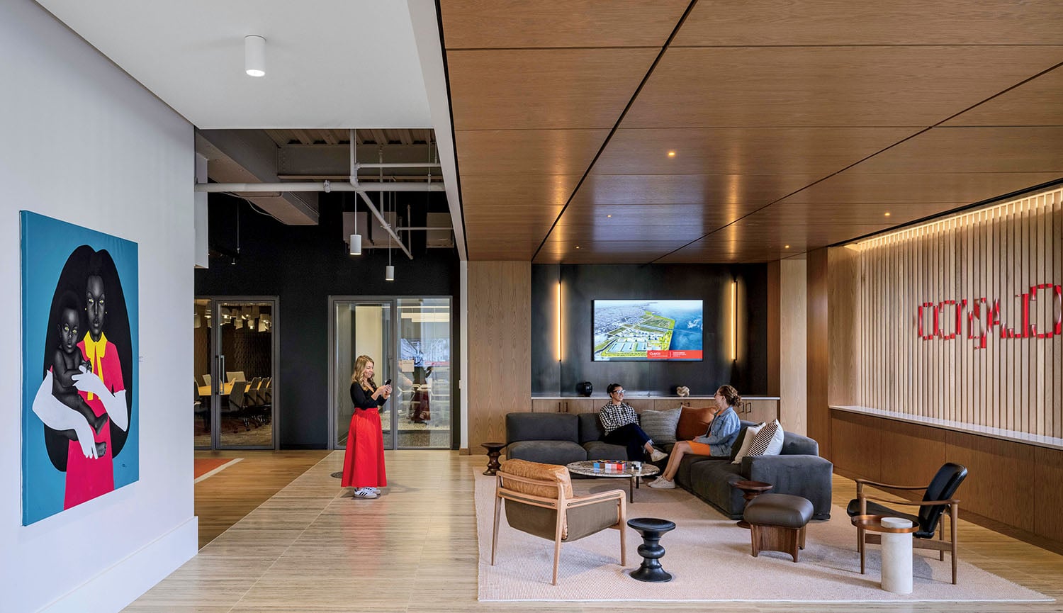 A couple sitting in a living room with a large painting on the w.