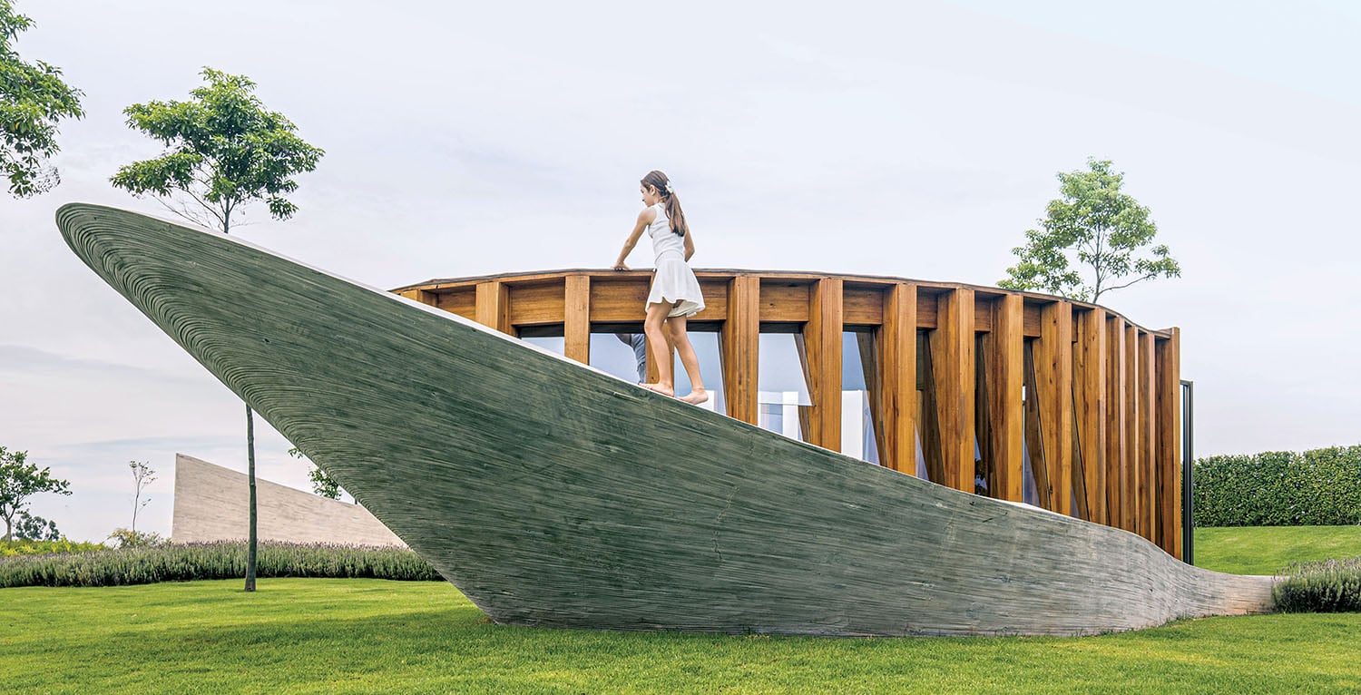 A woman standing on a wooden structure in the grass.