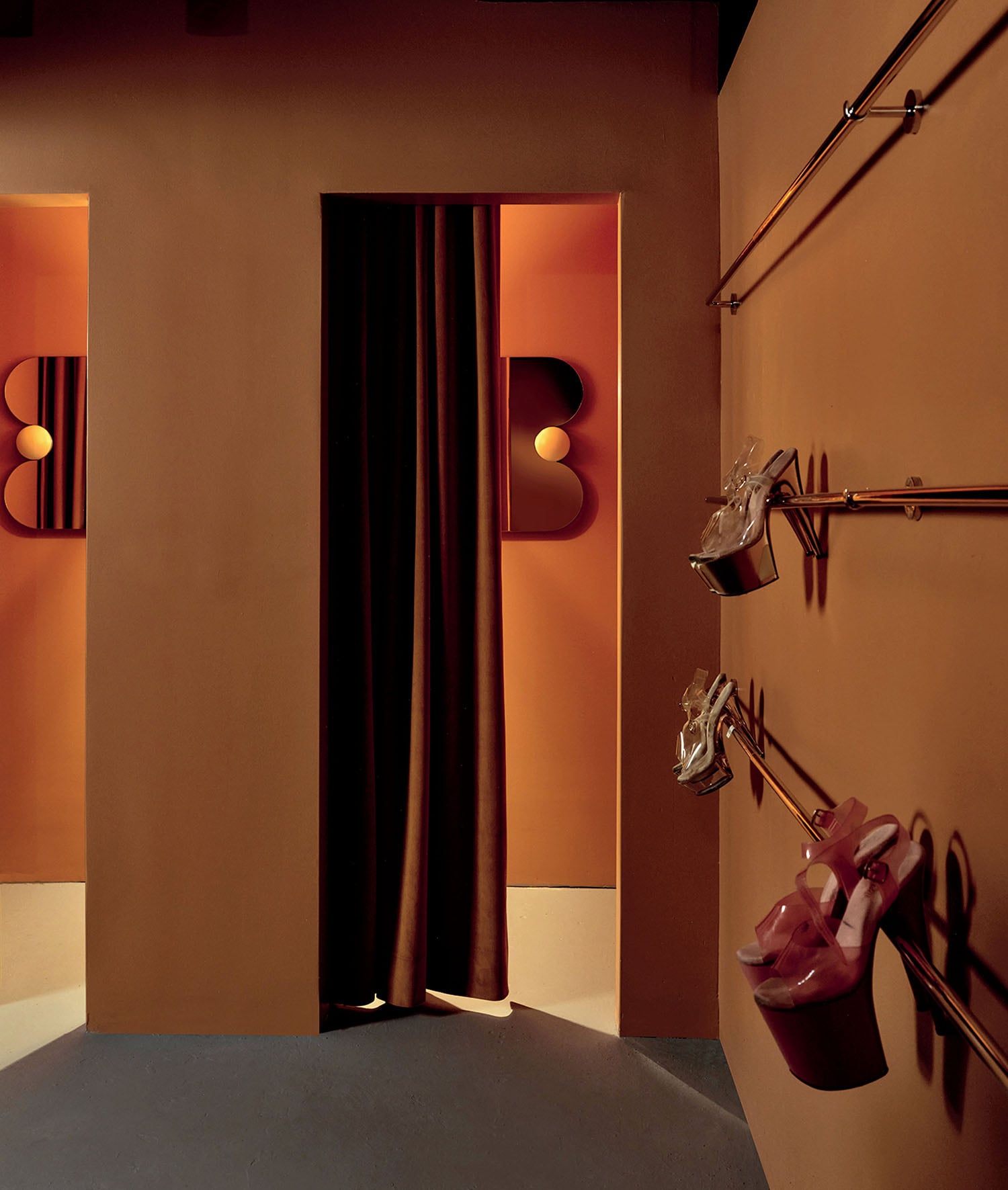 Dressing room area with orange walls, brown curtain, pink ballet pointe shoes on gold wall rods, and stylized wall-mounted B-shaped lights.