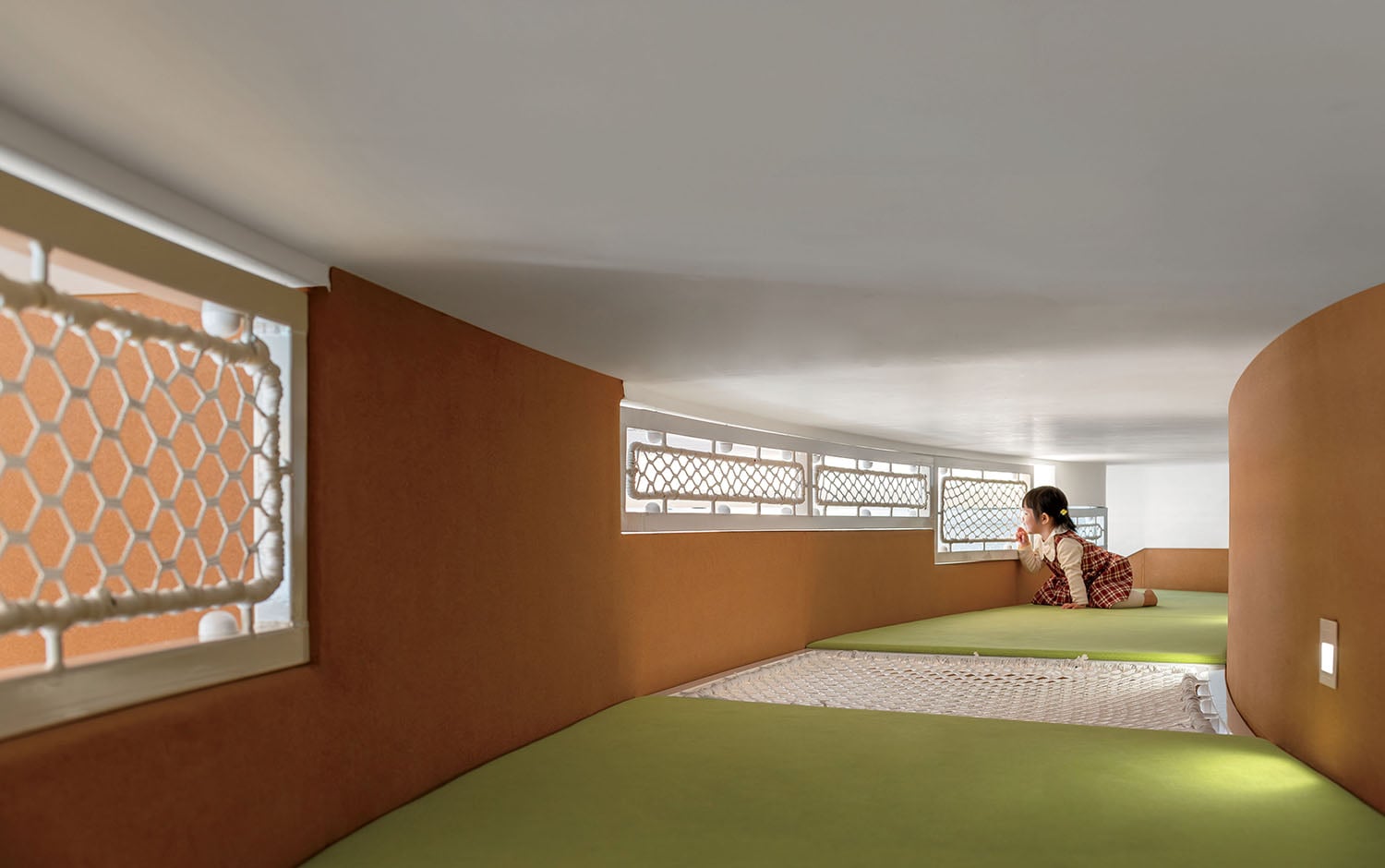A woman sitting on a green floor in a room.