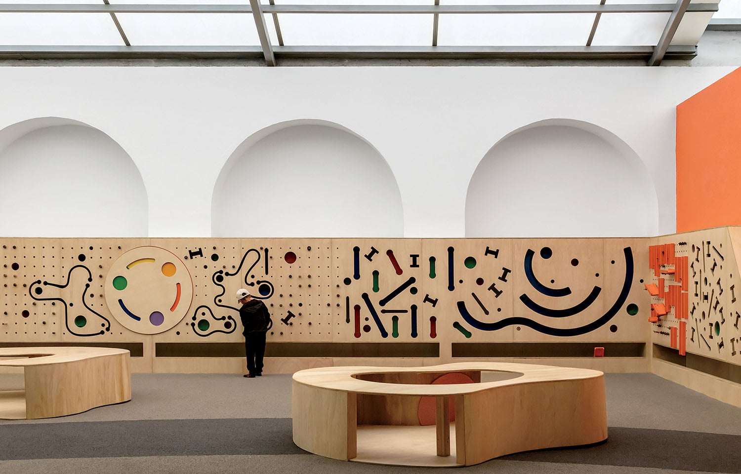 A man standing in a room with a wall of different shapes.