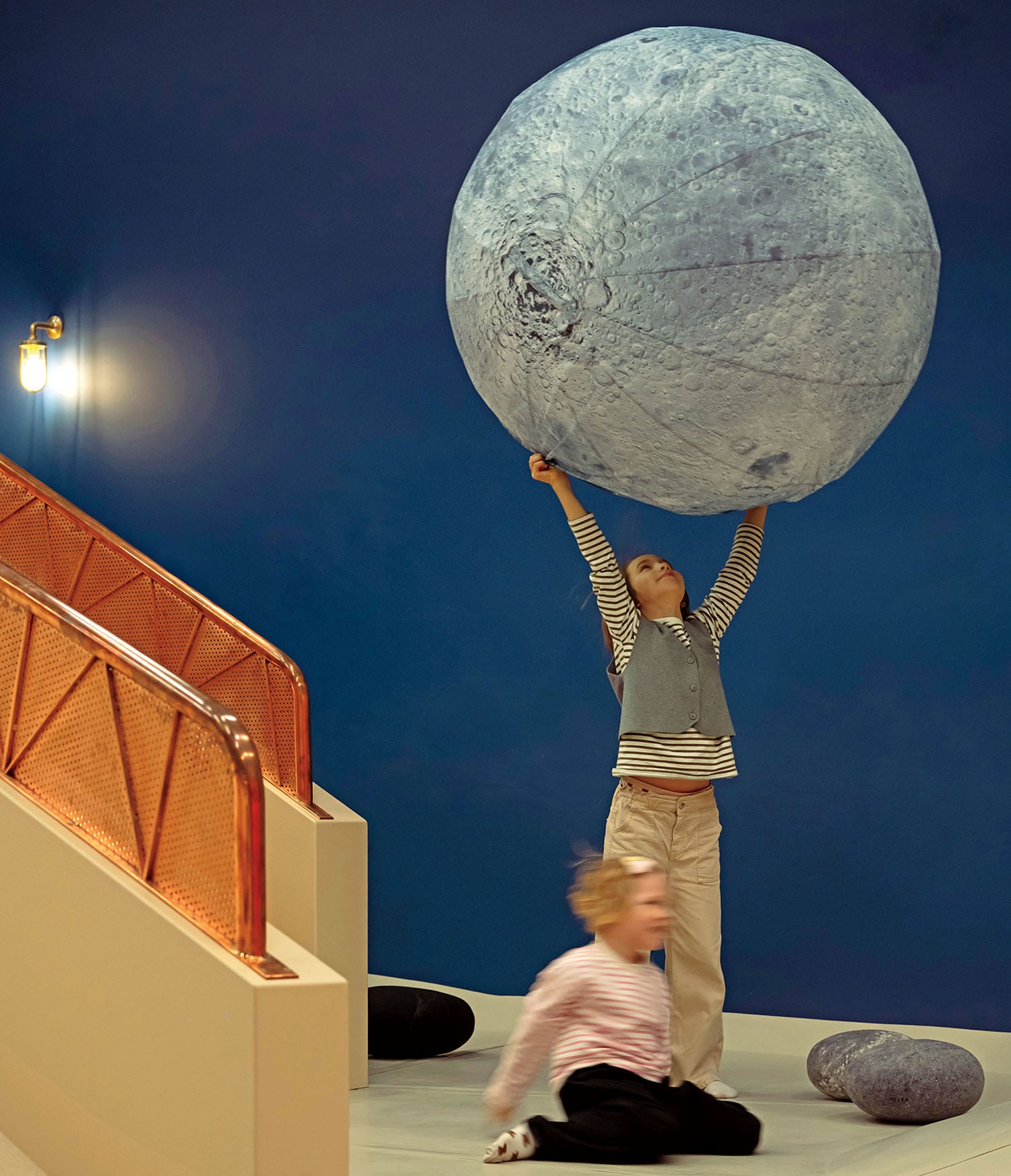 A child is holding a giant rock on his head.