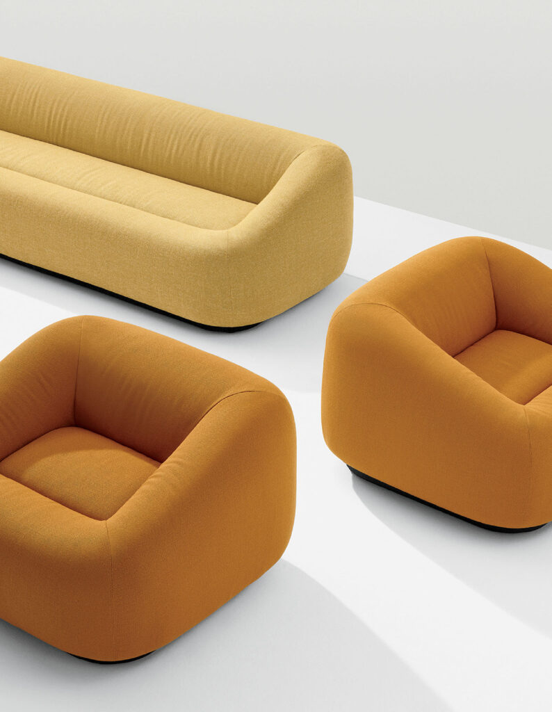 A yellow sofa and two orange armchairs with rounded, modern designs are placed on a white surface.