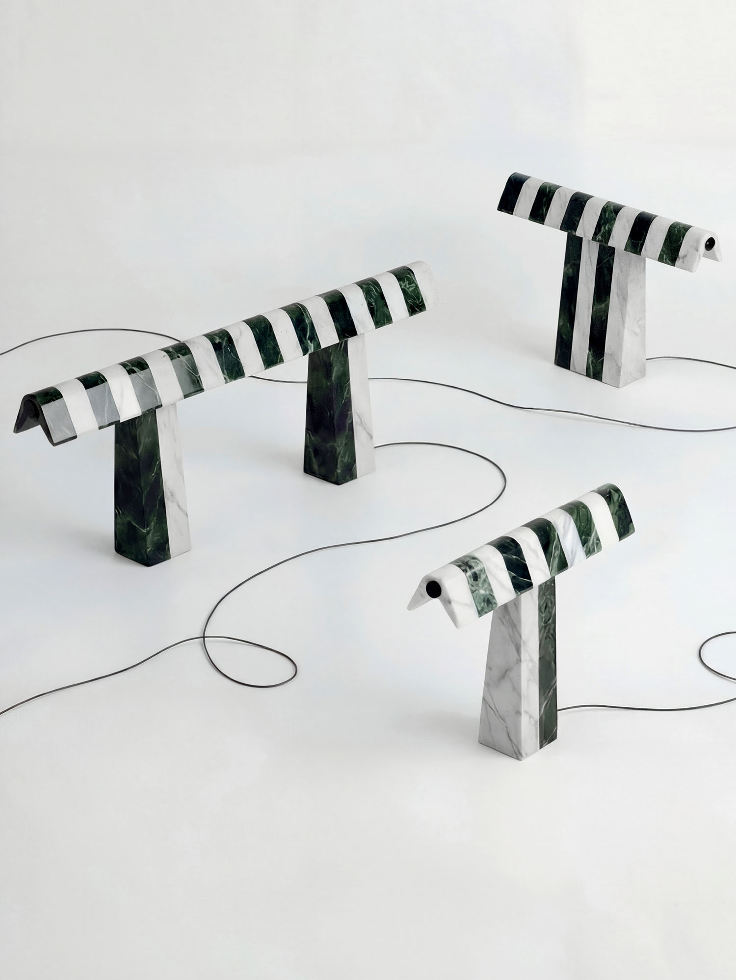 Four striped marble lamps with alternating green and white patterns are displayed on a white surface, each connected by visible black cords.