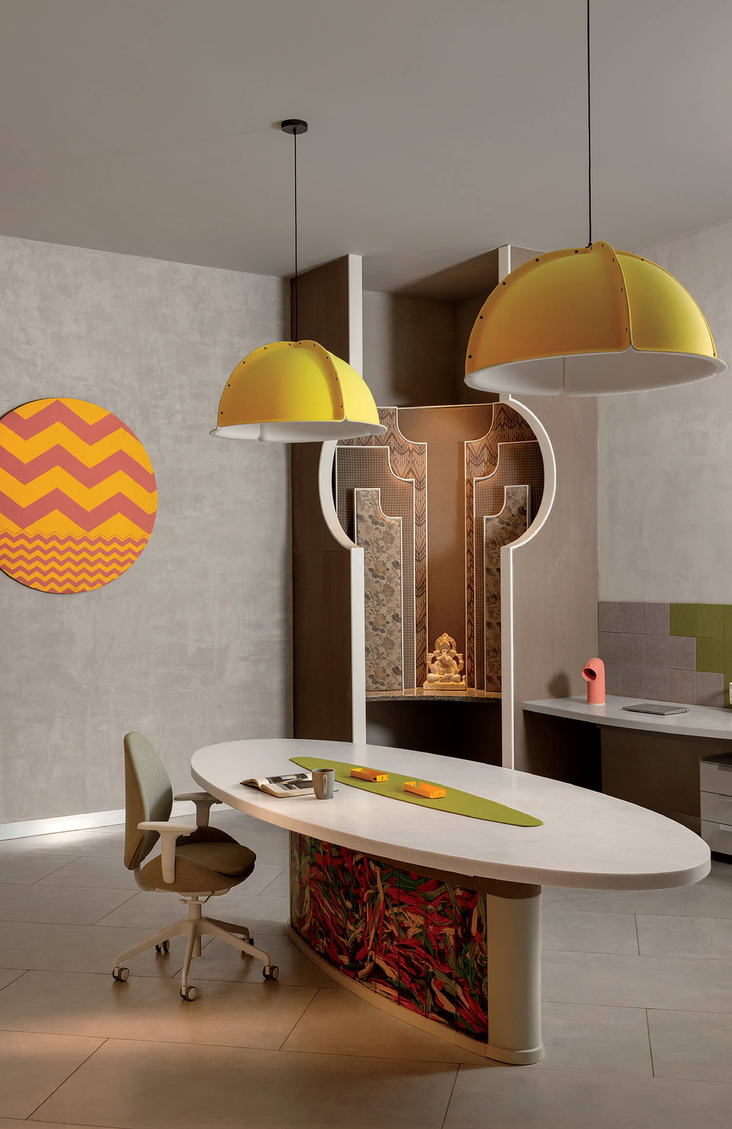 Modern office with a curved white desk, office chair, yellow dome pendant lights, decorative wall art, and a small statue in an ornate alcove.