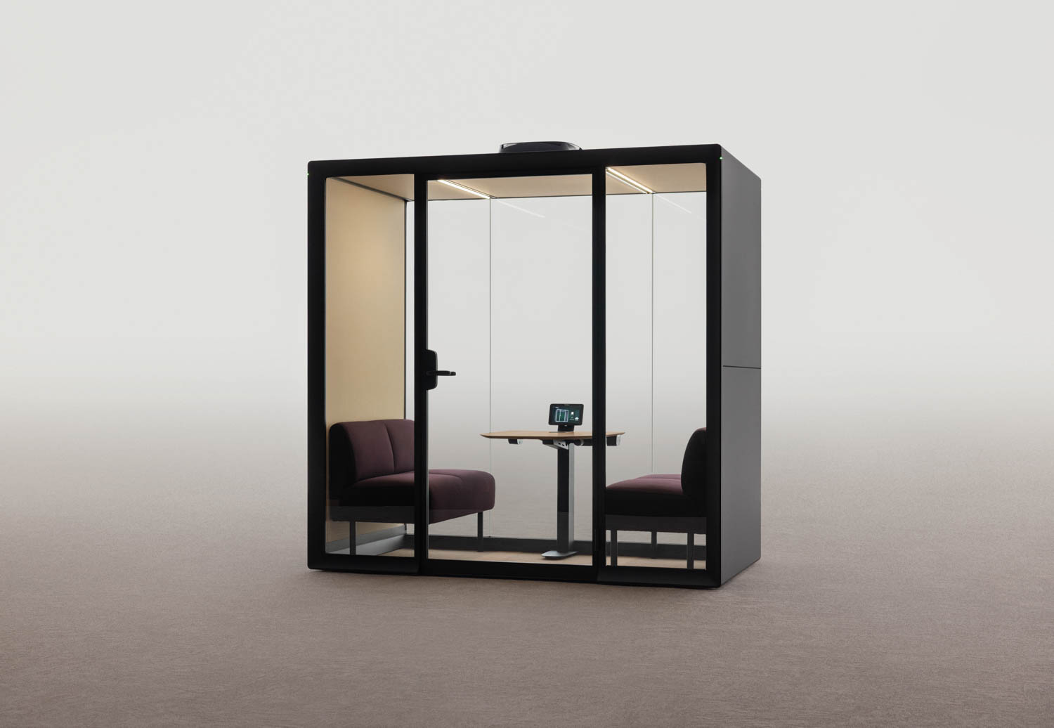 A modern Framery glass-walled office pod with two chairs, a small table, and a tablet device inside, set against a plain light background.