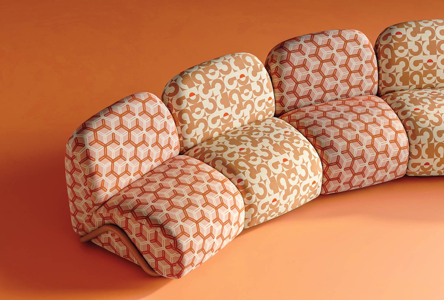 A modular sofa with three seats upholstered in retro geometric and abstract patterns in shades of orange, beige, and cream, set against an orange background.
